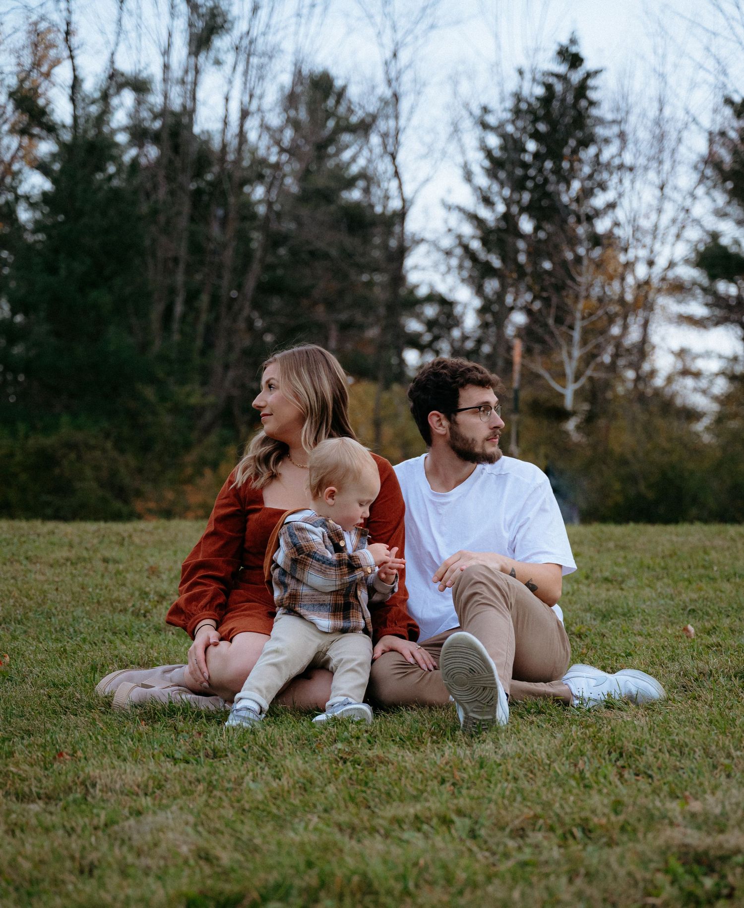 Romantic couple lounges together on grassy hillside during outdoor photo session.
