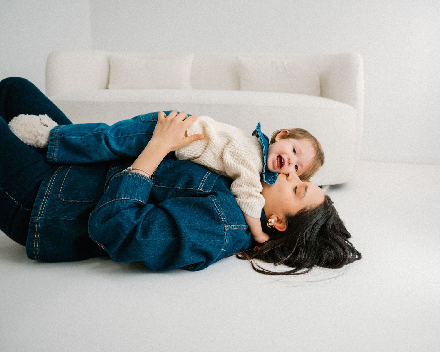 Relaxed lifestyle photos of parent and child lounging on white sofa.