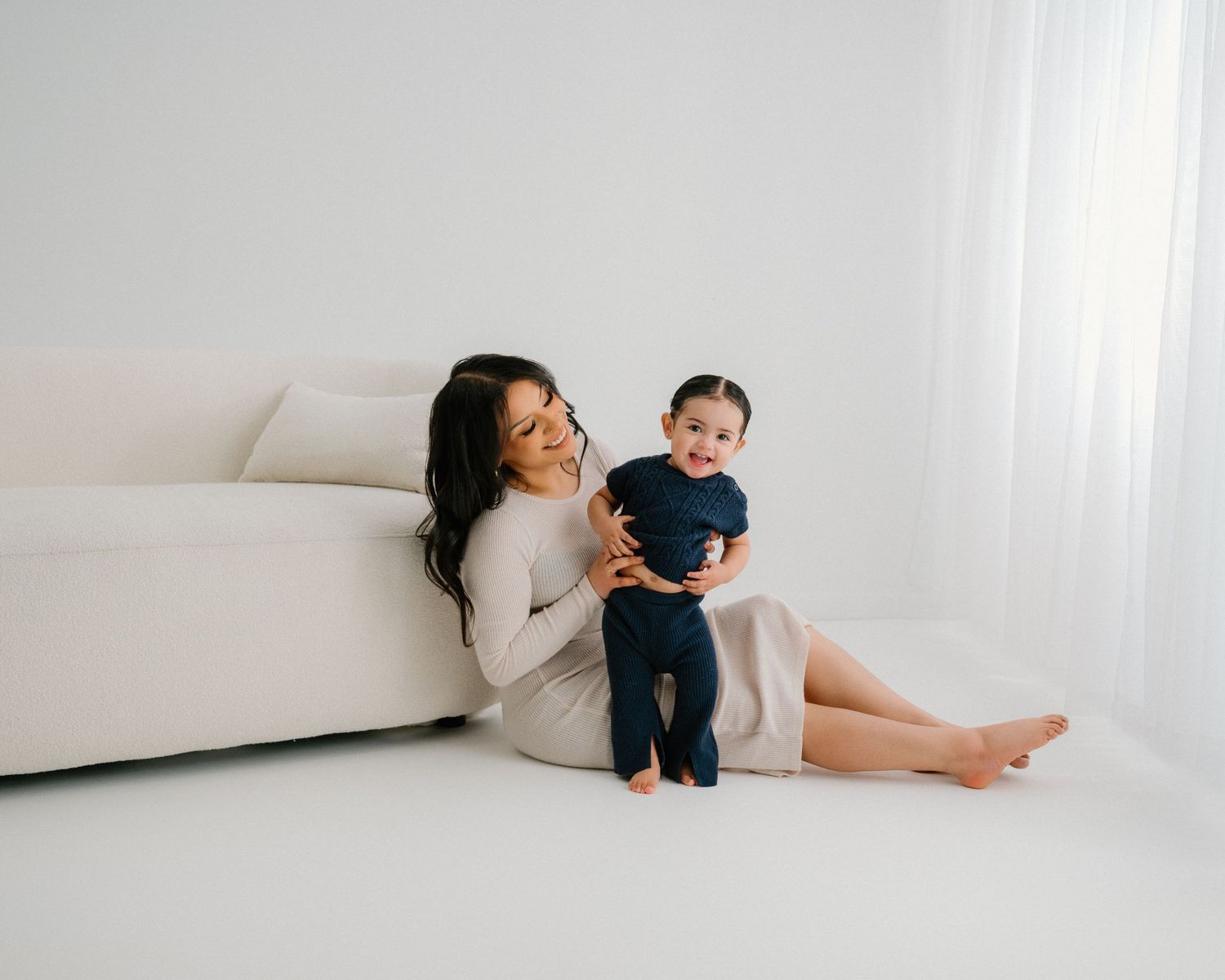 A casual indoor family photoshoot showing intimate moments against white backdrop.