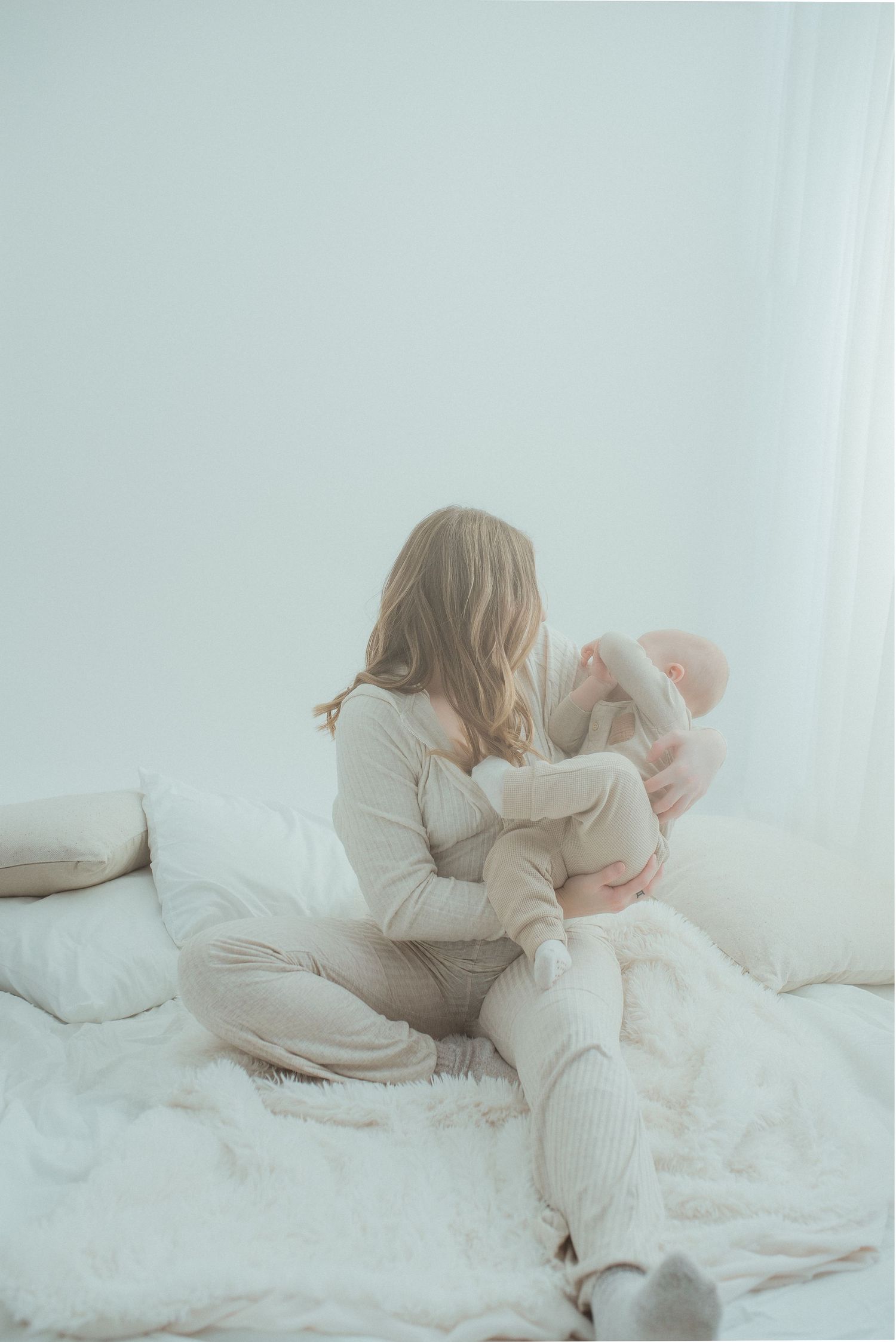 Dreamy sequence of figures in white lying on soft bedding in natural light.