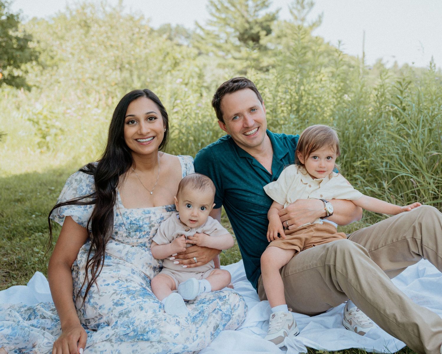 A family relaxes on a blanket during an outdoor summer photoshoot.