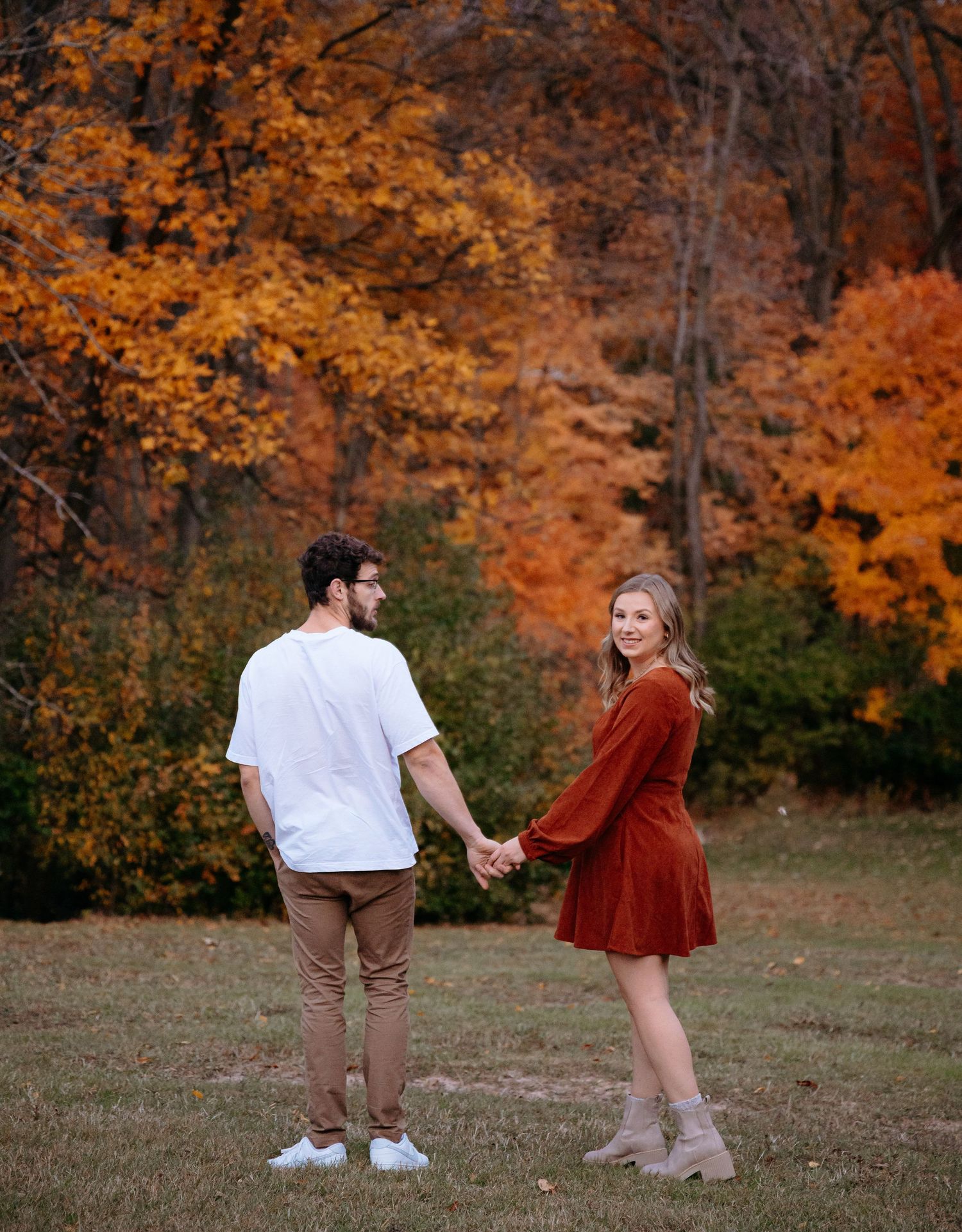 Couple twirling and dancing in an autumn field with vibrant orange foliage. Appleton, Green Bay & Kaukauna