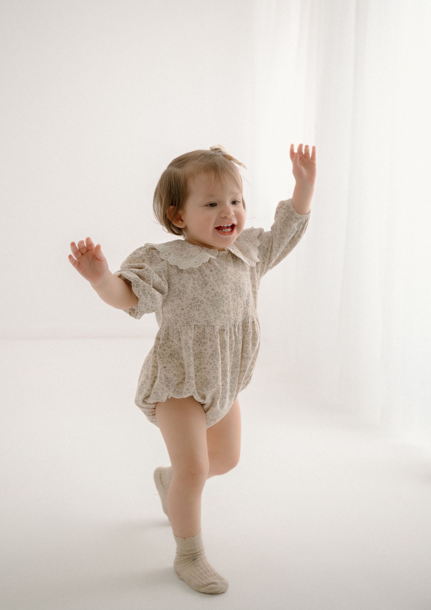 Baby in floral dress dancing and playing in white studio setting. Appleton, Green Bay & Kaukauna