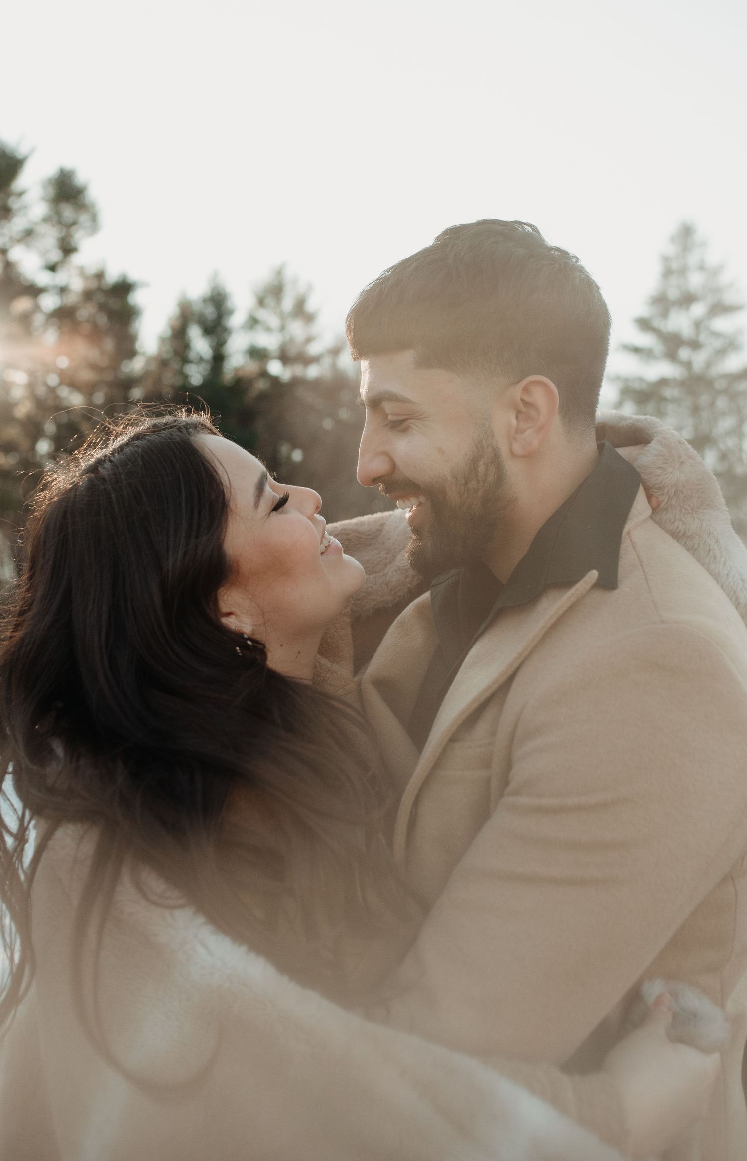 Romantic couple poses in soft light with tan coat and intimate expressions in winter setting. Appleton, Green Bay & Kaukauna