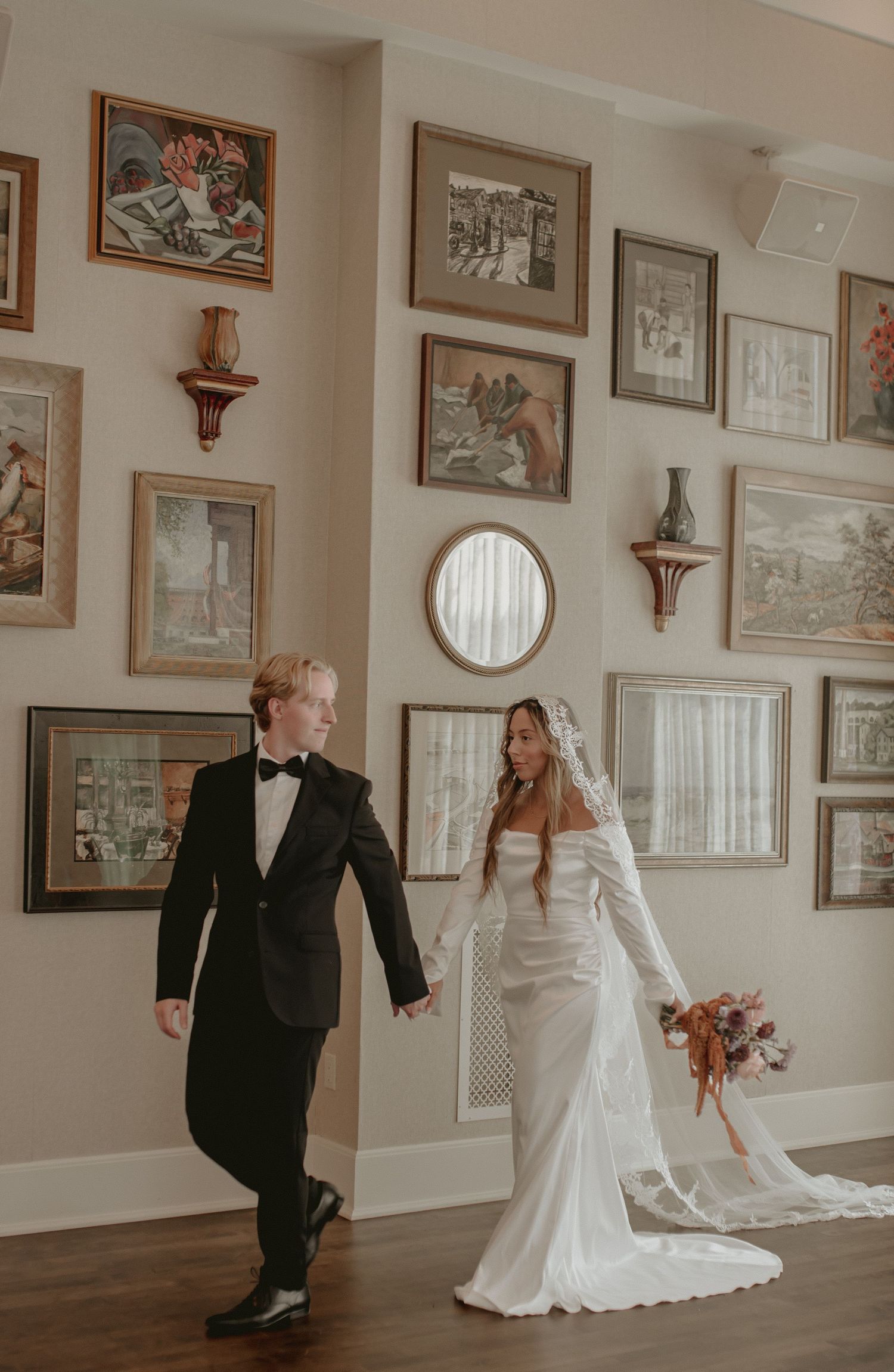 A couple dances in a gallery hallway lined with framed artwork and vintage photographs.