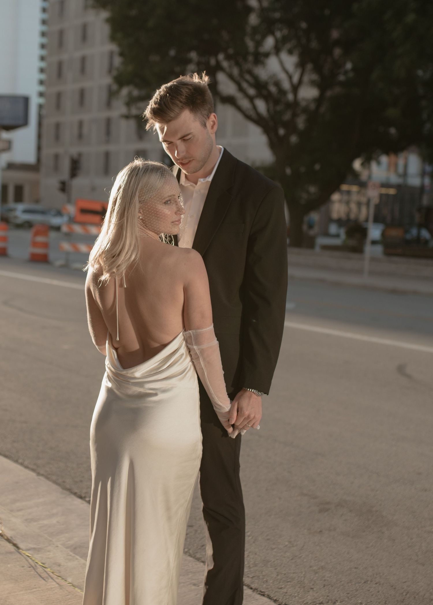 Intimate sunset portrait of couple in formal attire on urban street.