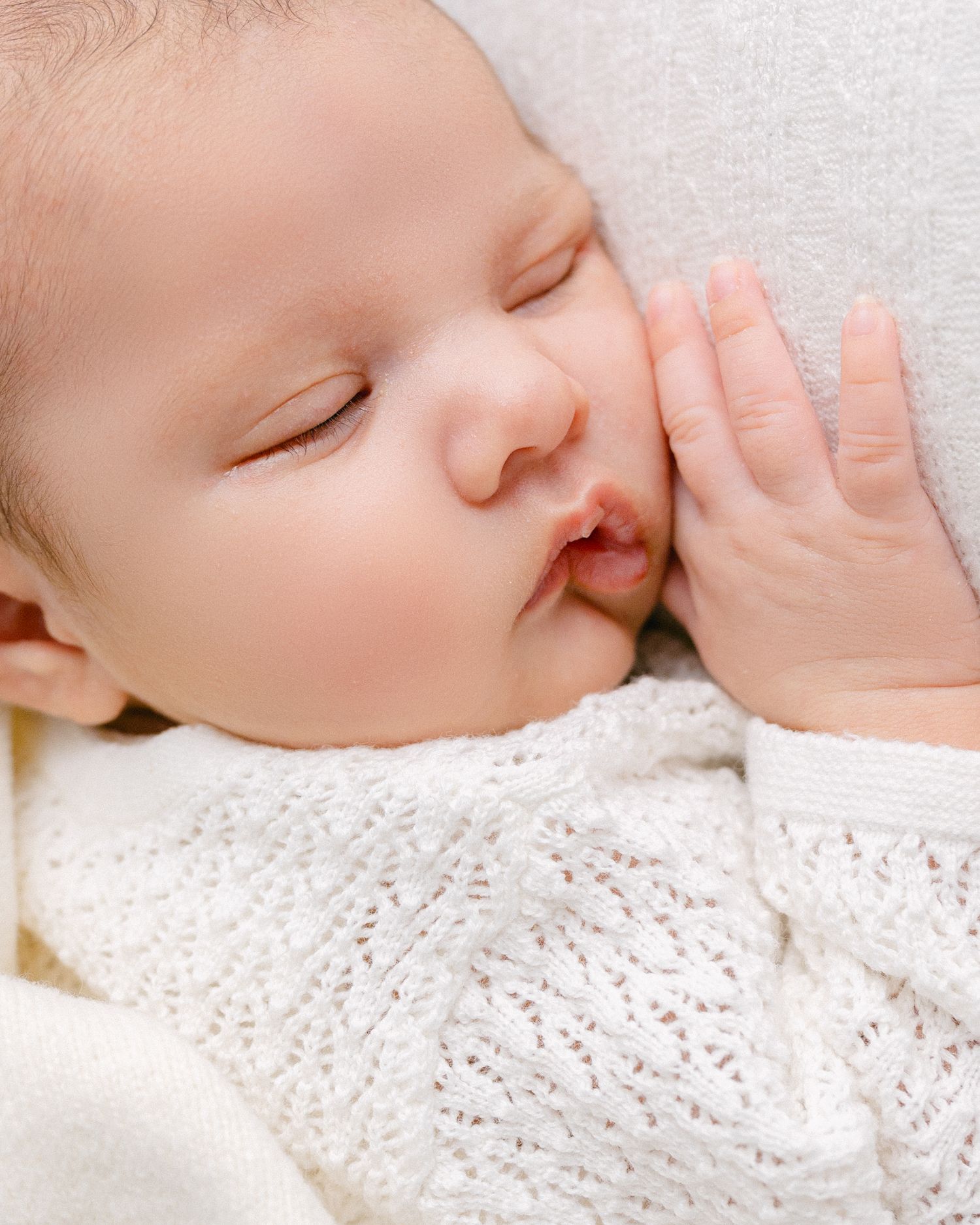Close up details of sleeping infant on white textured fabric. Appleton, Green Bay & Kaukauna