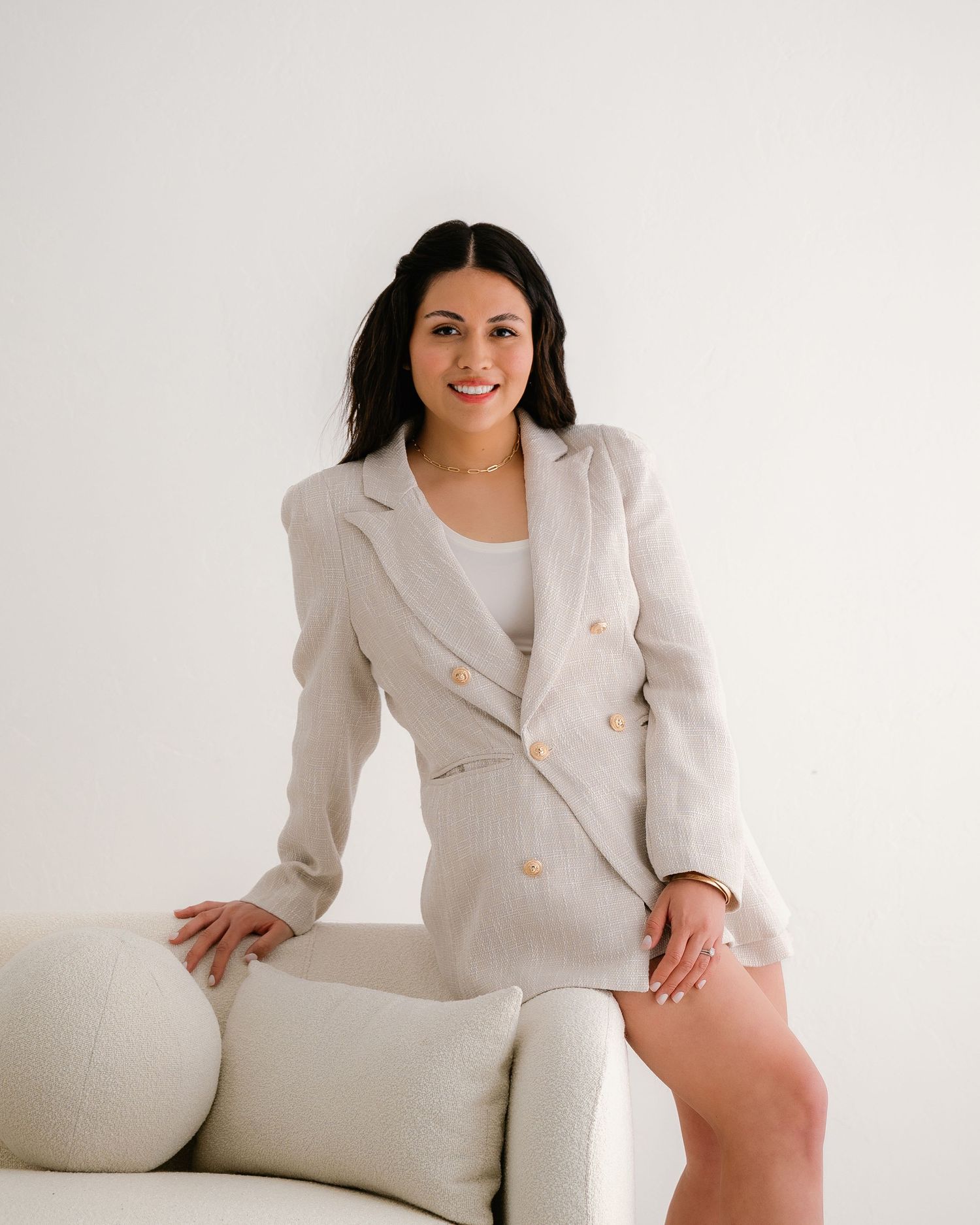 Fashion photo series of a model in white blazer lounging on light colored couch.