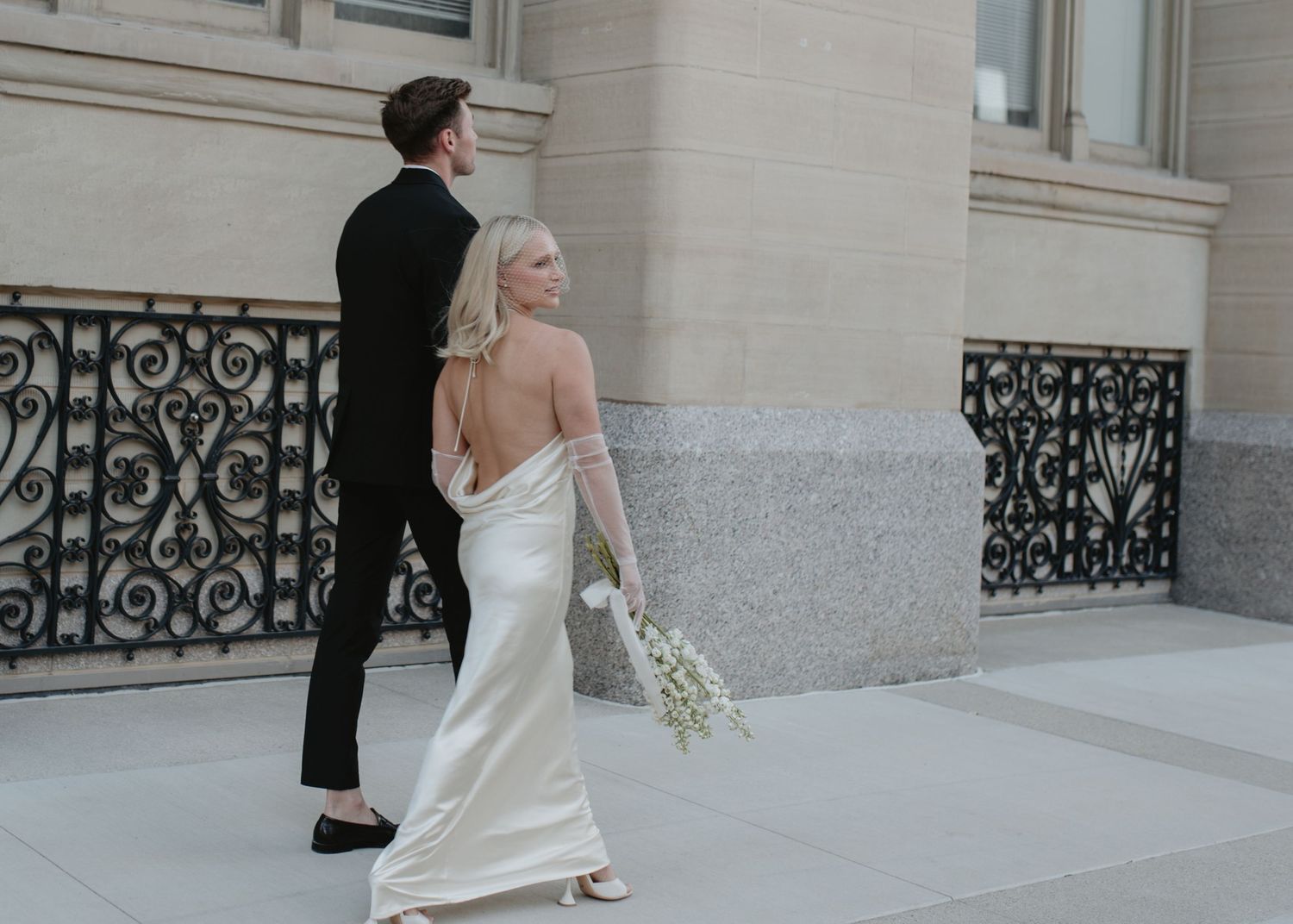 Romantic wedding photoshoot against ornate architectural columns and ironwork.