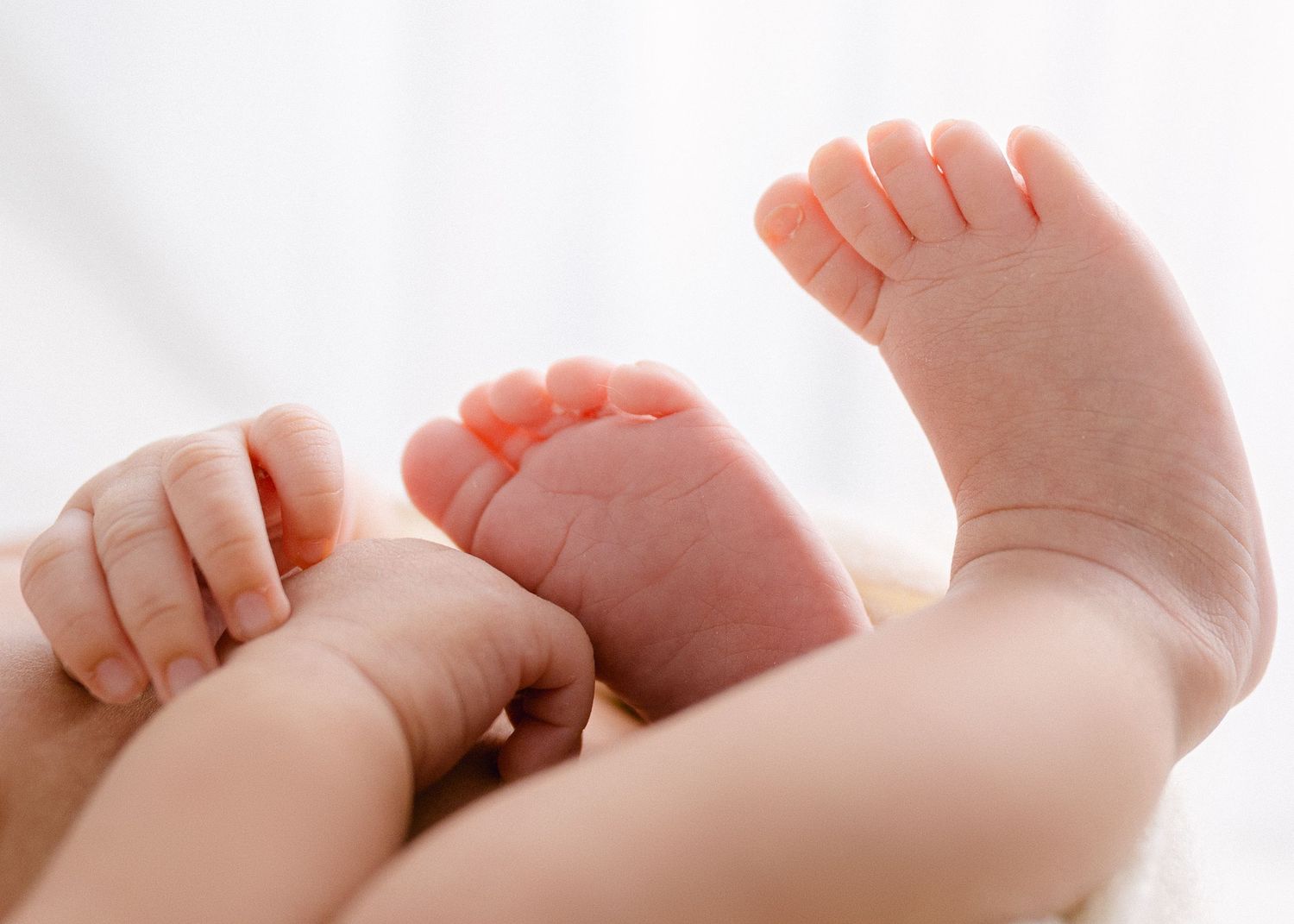 Row of tiny baby feet lined up on white linen fabric. Appleton, Green Bay & Kaukauna