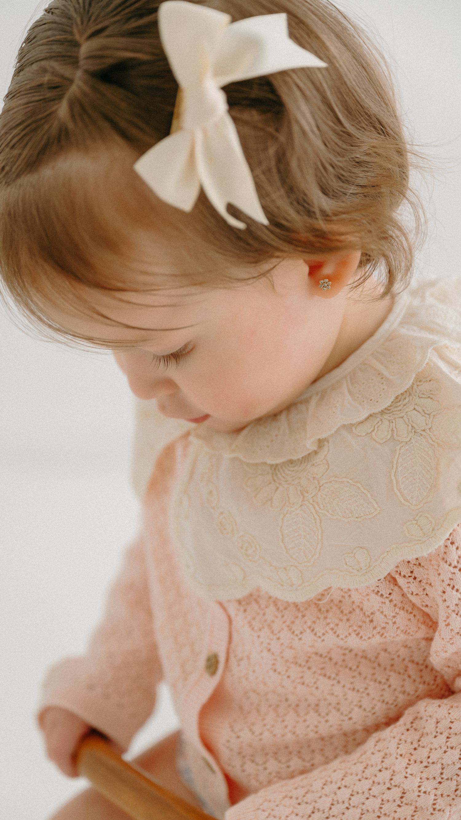 Close-up of cream bow hair accessory and lace collar detail. Appleton, Green Bay & Kaukauna