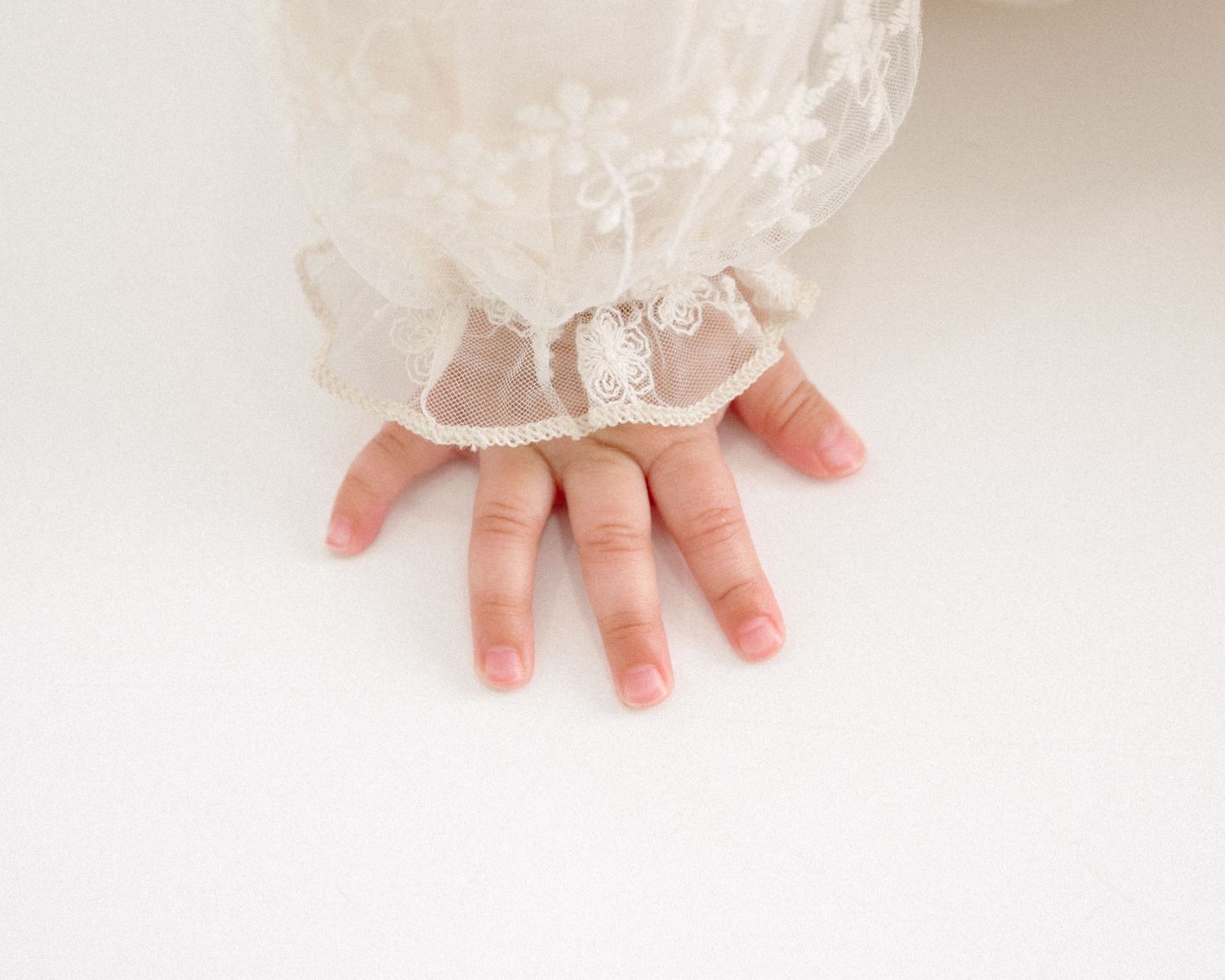 Close-up view of tiny baby hands reaching out against white backdrop. Appleton, Green Bay & Kaukauna
