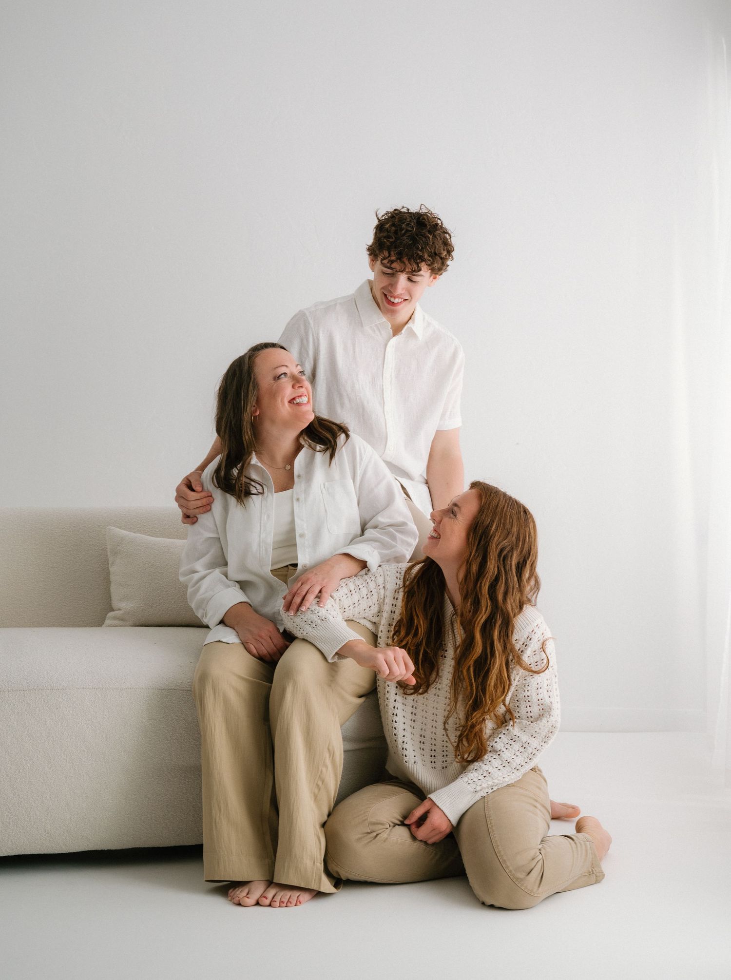 Candid family portrait showing genuine laughter and connection on a white couch.