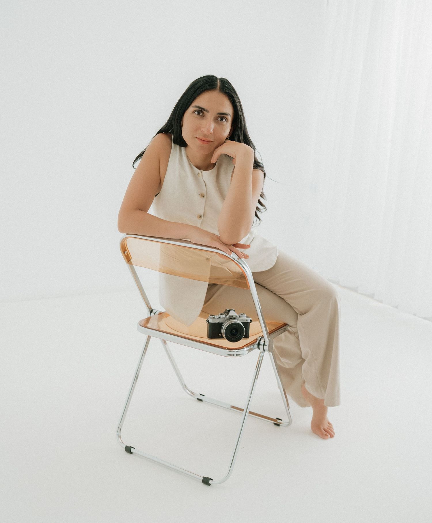 Woman in cream outfit sitting on folding chair with vintage camera. Appleton, Green Bay & Kaukauna
