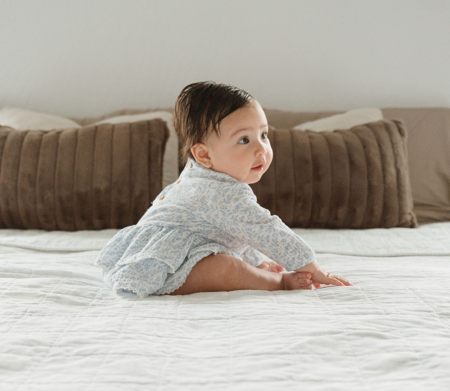 Sequence showing baby in white onesie crawling on white bedding.