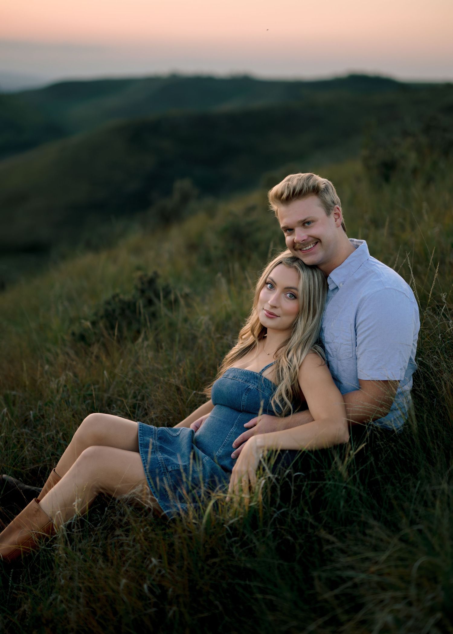 A couple shares intimate moments on a hillside at sunset in a series of romantic outdoor photos.