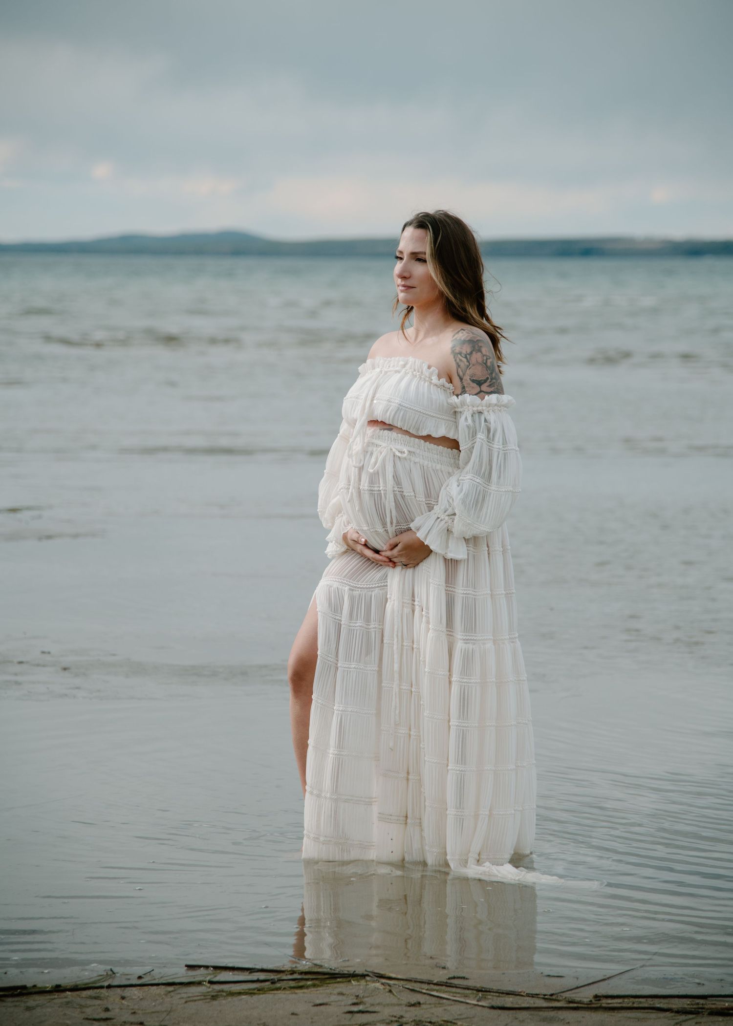 Soft muted tones capture ethereal white dress against coastal landscape. Calgary Alberta Maternity Photographer.