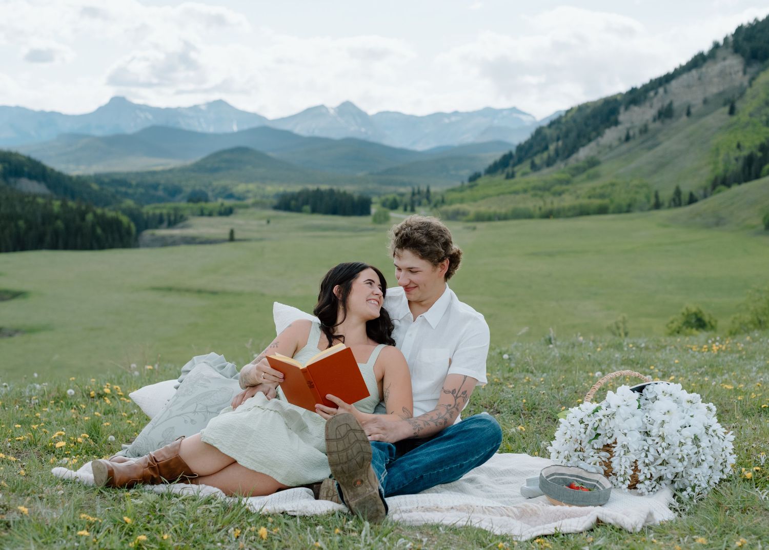 Couple having a romantic picnic with books in a scenic mountain meadow filled with wildflowers in Calgary, Alberta Calgary Lifestyle   Photo