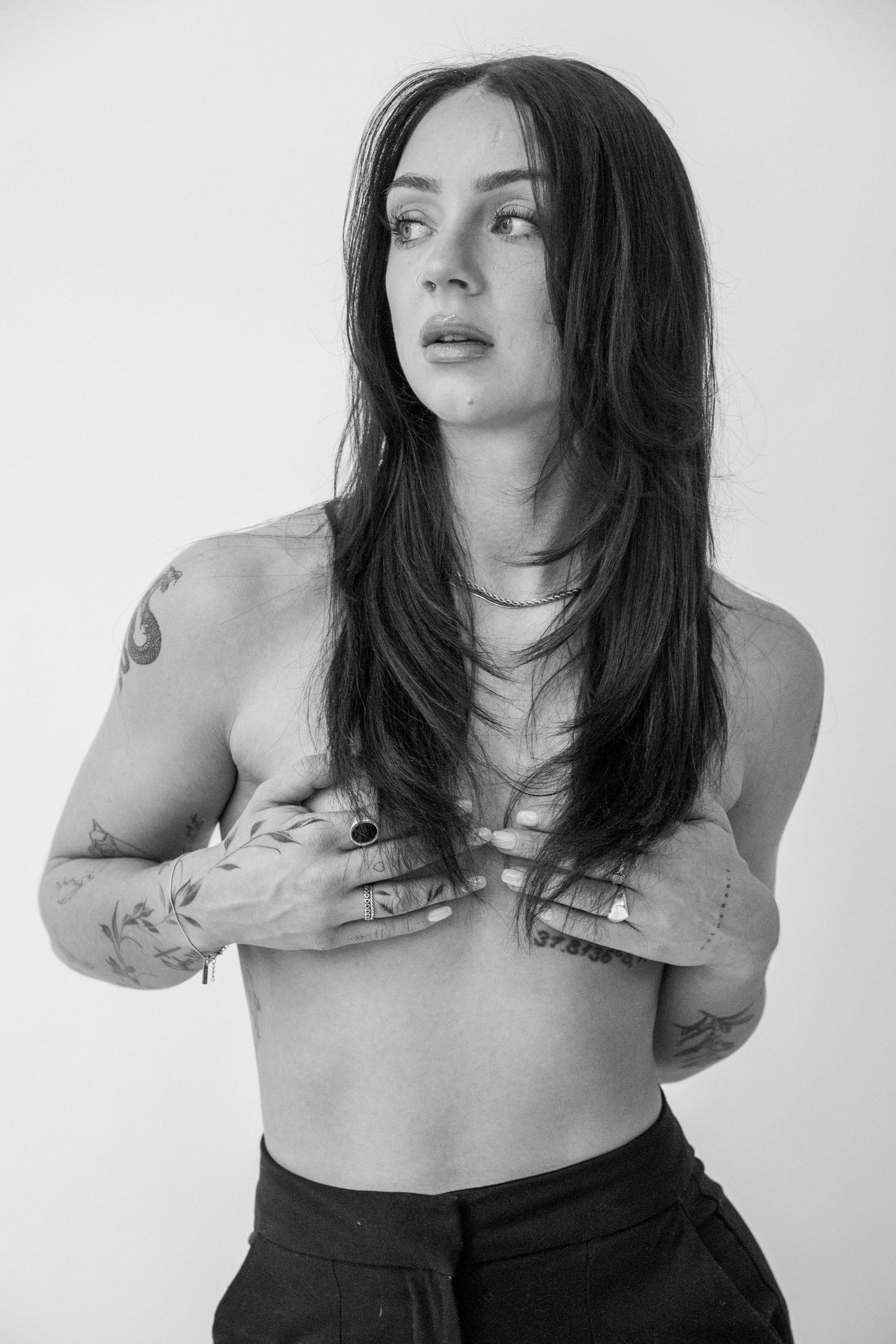 Black and white portrait showing tattoos and layered necklaces in an artistic pose. Calgary Alberta Branding Photographer.