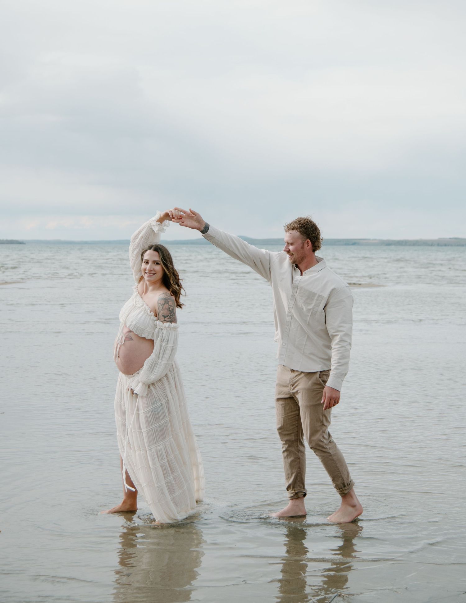 Romantic beach maternity shoot with couple dancing in shallow water. Calgary Alberta Maternity Photographer.