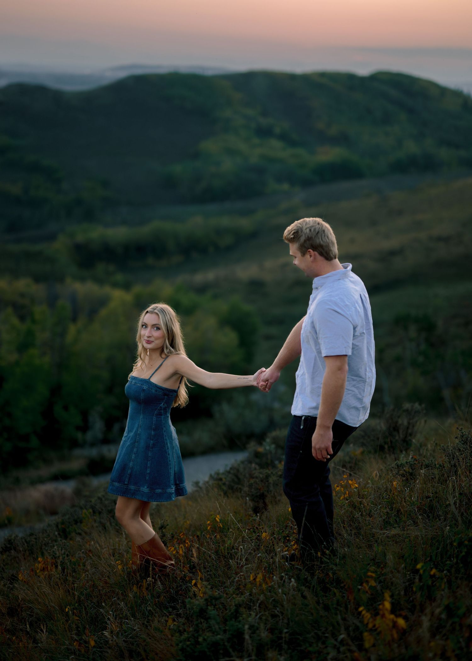 Couple in a scenic mountain landscape sharing intimate dance-like poses at sunset.