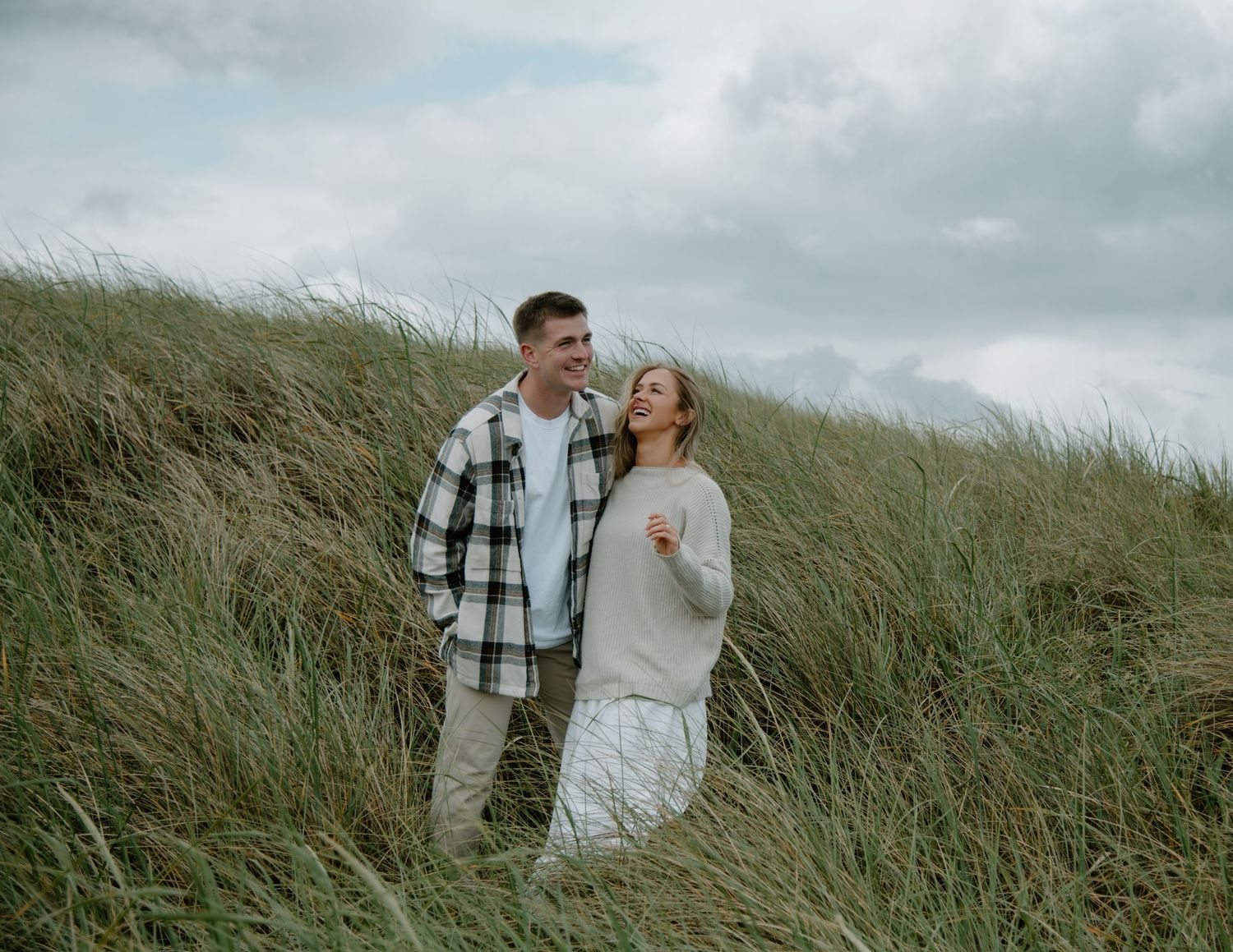 A romantic moment captured between a couple in coastal grassland under moody skies on Oregon Coast. Calgary Lifestyle and Engagement.
