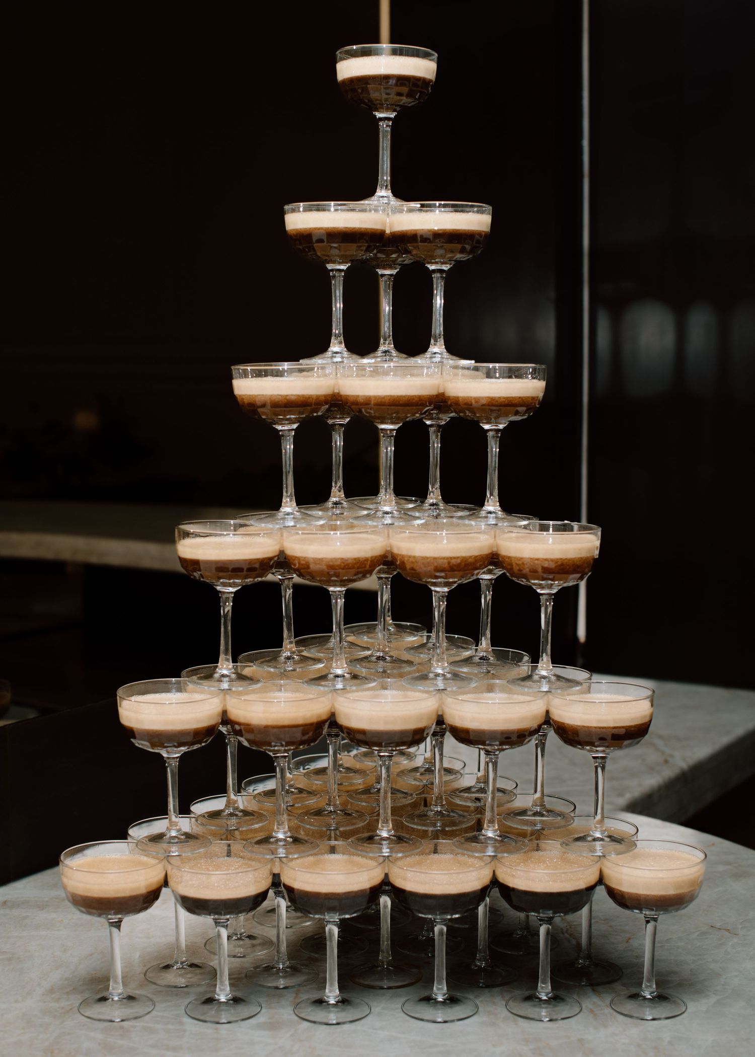 A champagne tower created with coupe glasses arranged in layers for an elegant wedding celebration at the Studio at Vic Park YYC Wedding
