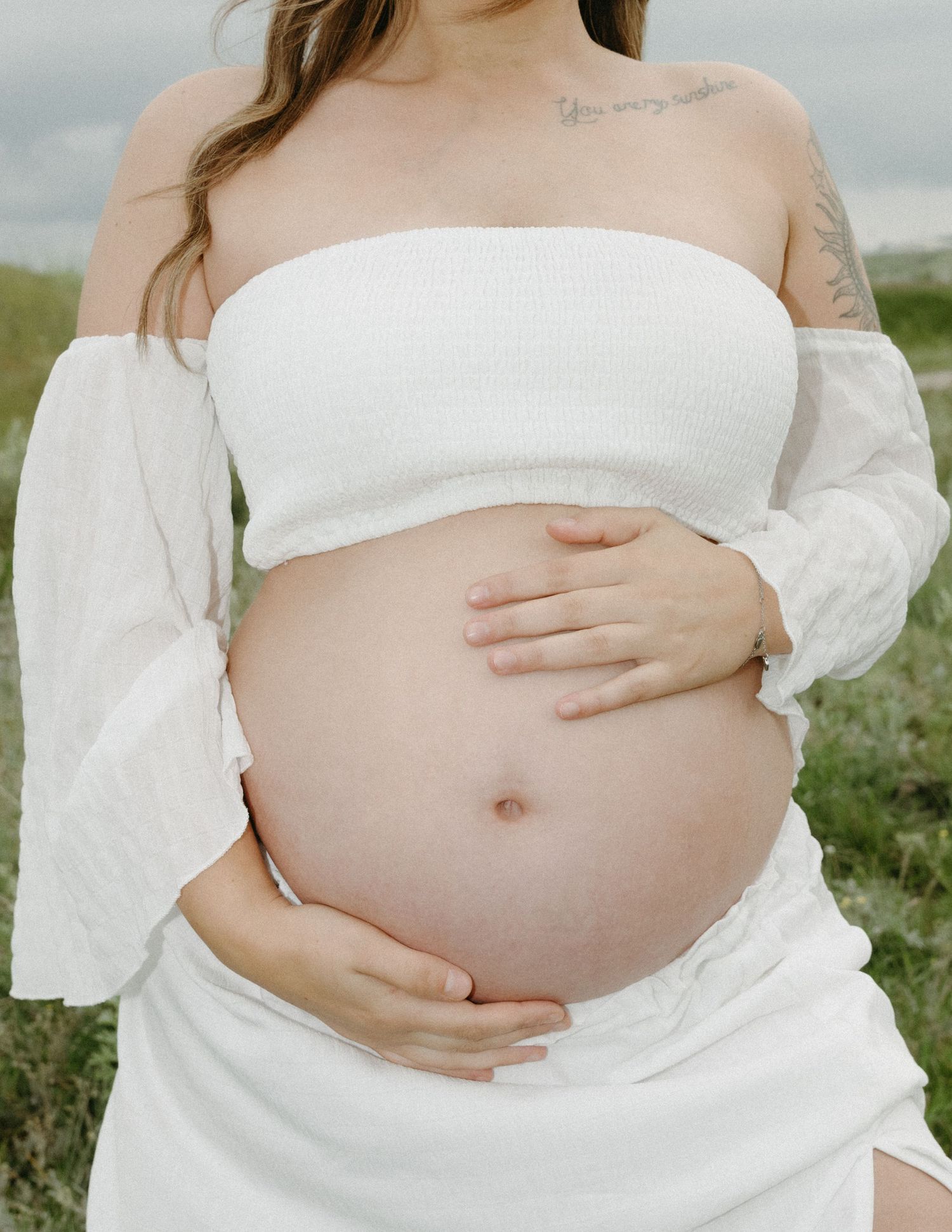 A series of maternity photos showing a pregnant belly in a white dress against a natural outdoor background.
