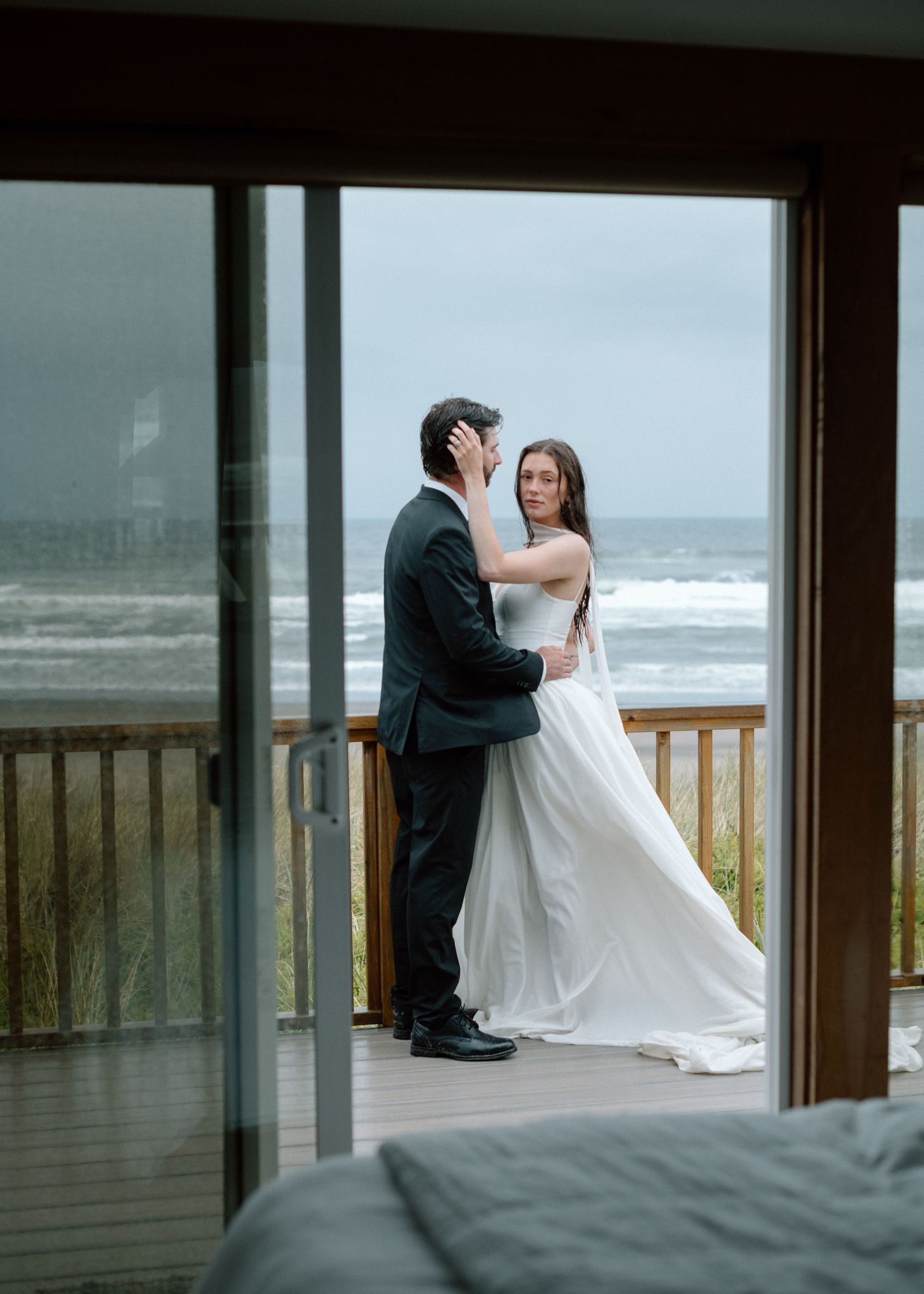 Wedding couple share romantic moments on a beach deck overlooking the ocean during their coastal celebration.