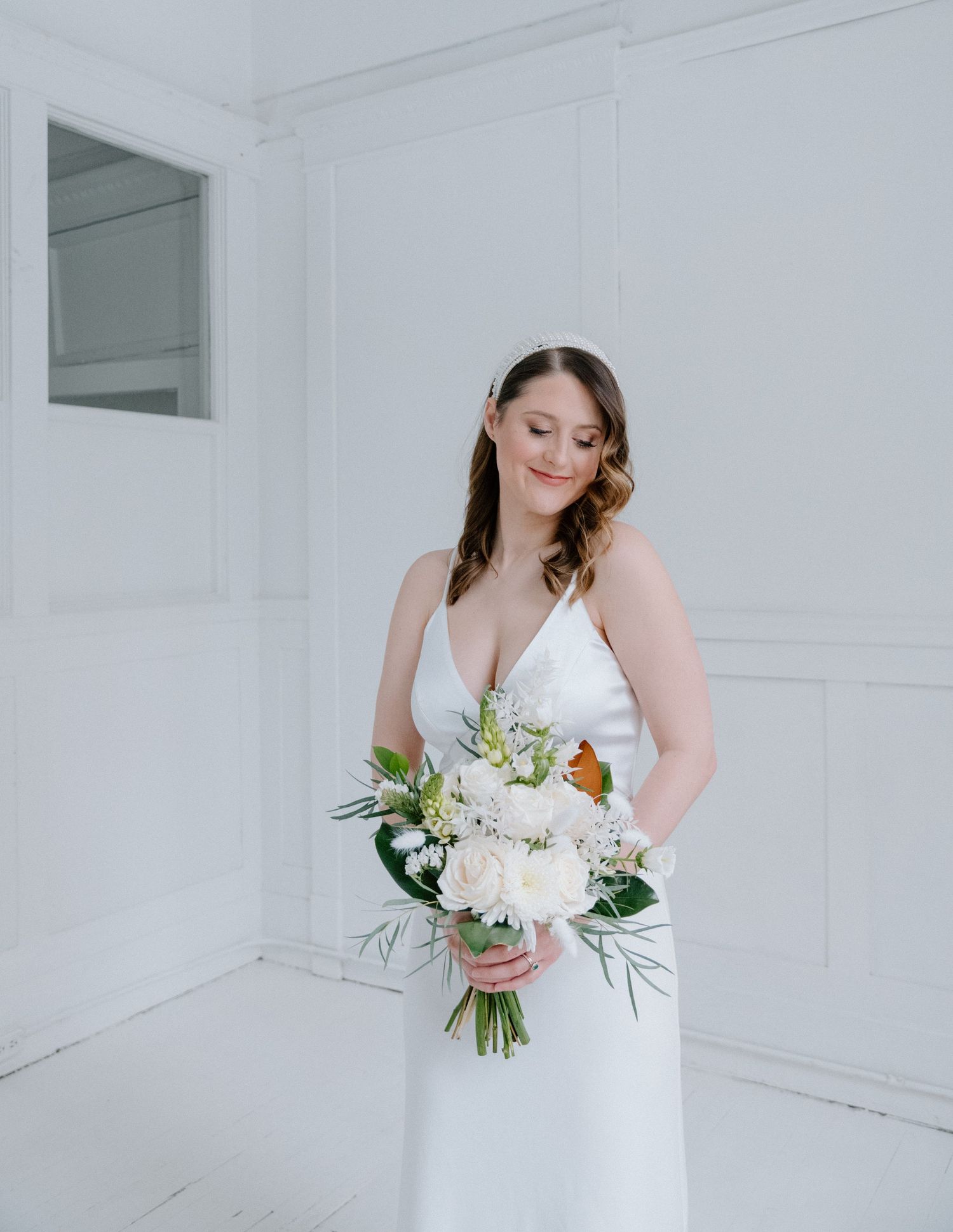 Bride in white dress holding a beautiful bouquet in bright studio setting at The Study Studios Calgary Wedding Photographer.