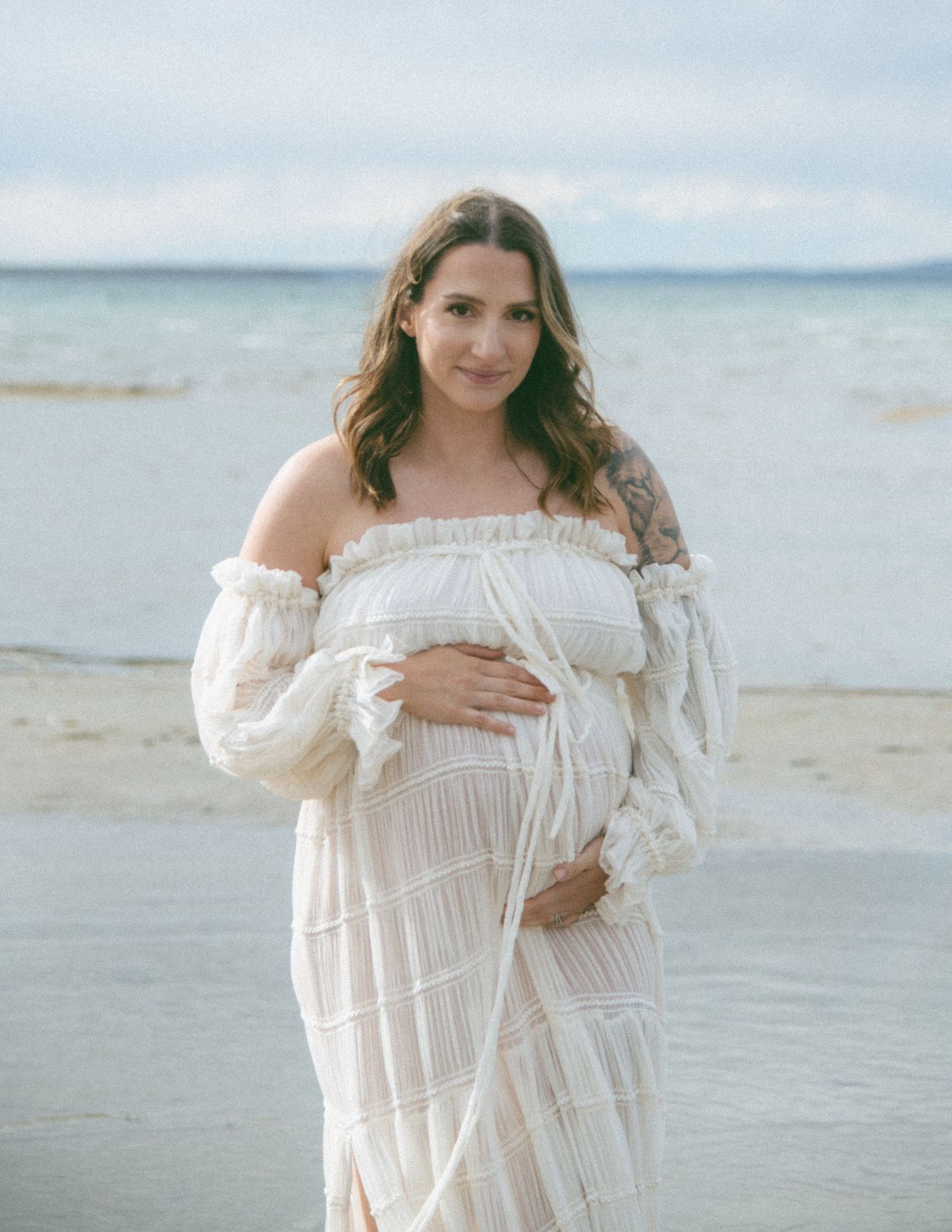 Serene beachside maternity portrait featuring white off-shoulder dress. Calgary Alberta Maternity Photographer.