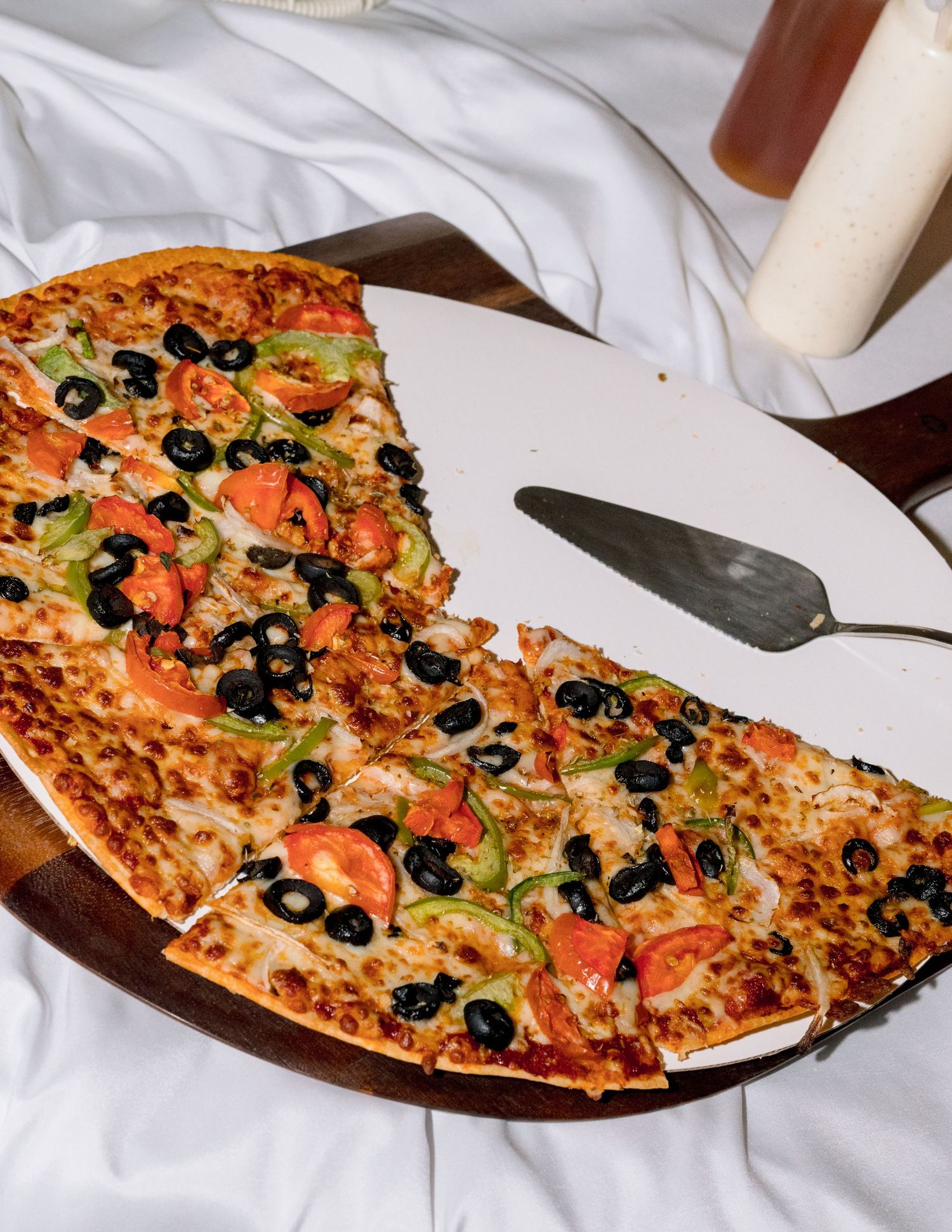 Close-up of a colorful pizza topped with olives and vegetables on white background.