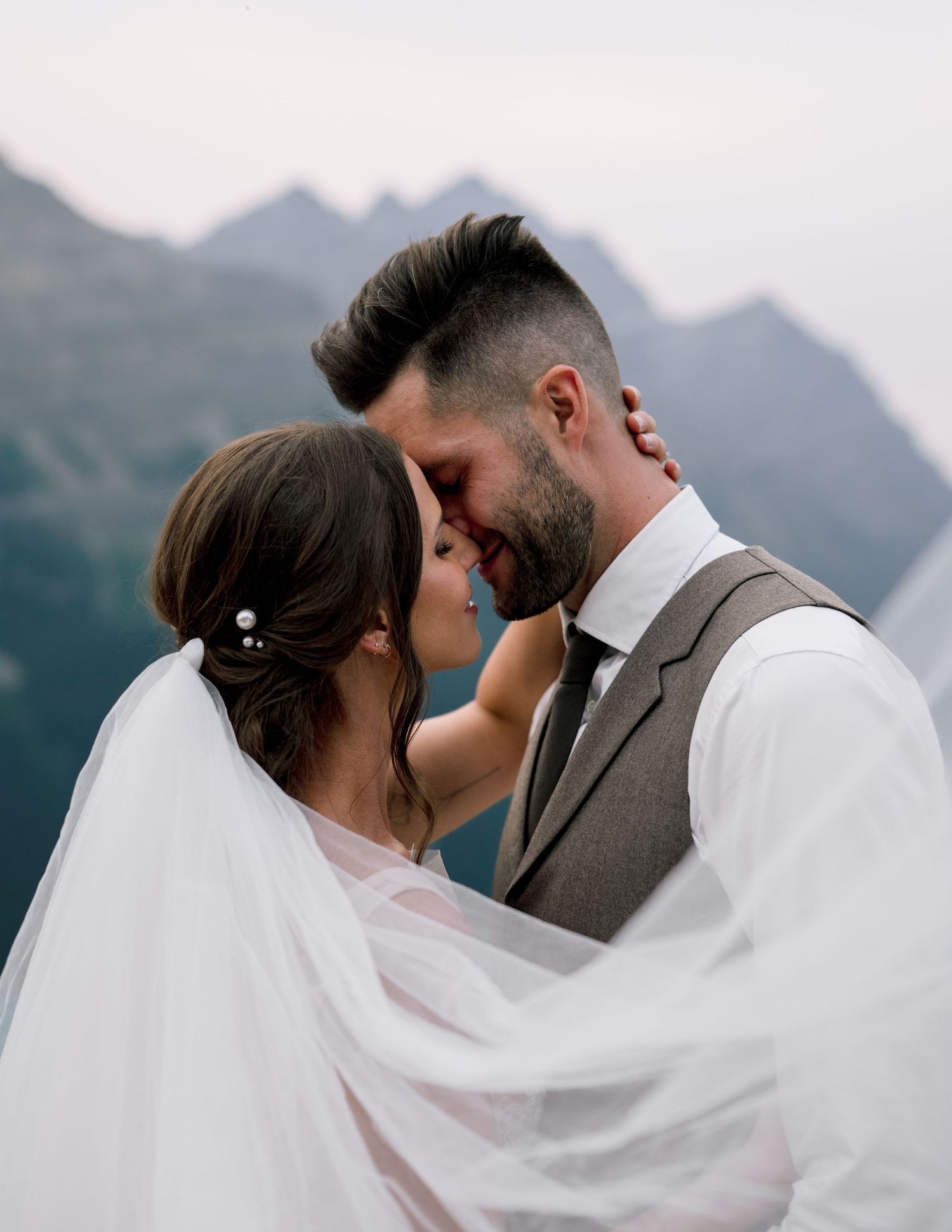 A romantic wedding couple sharing tender moments while surrounded by majestic mountain peaks.