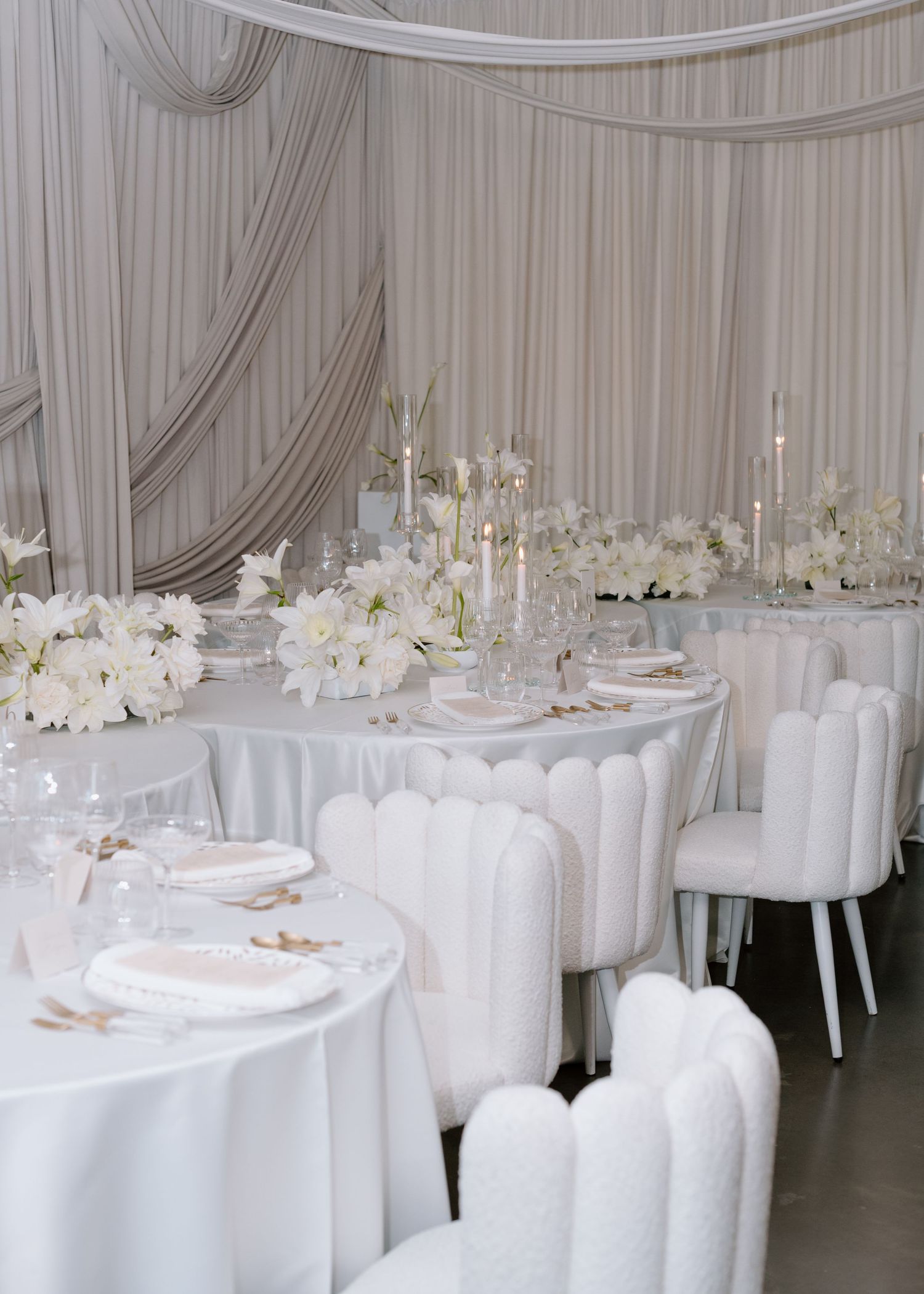 Luxurious all-white wedding reception setup with draped fabric, candles, and floral centerpieces at the Brownstone YYC. Calgary Wedding Phot