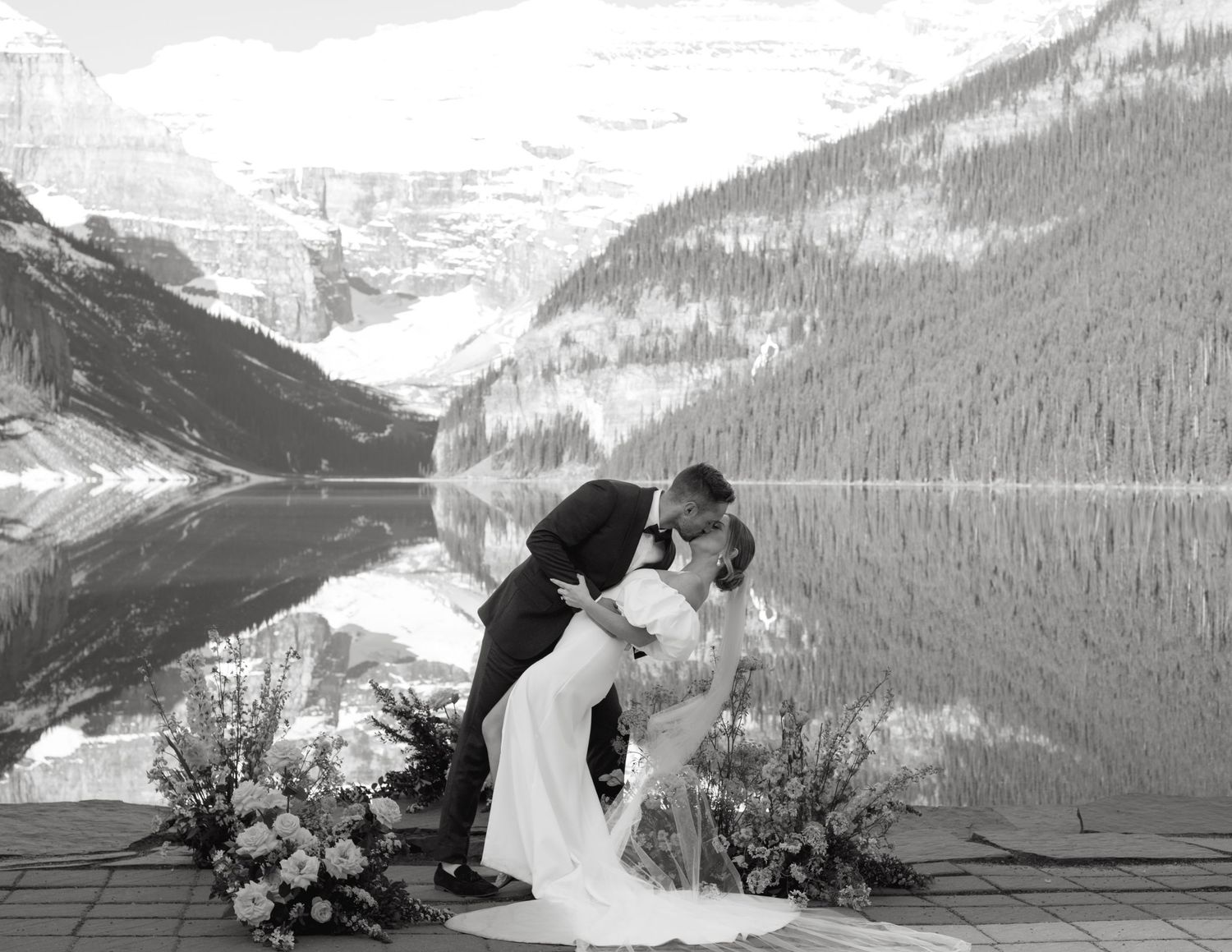 A romantic winter wedding ceremony takes place against a stunning mountain backdrop at Lake Louise in Banff National Park.