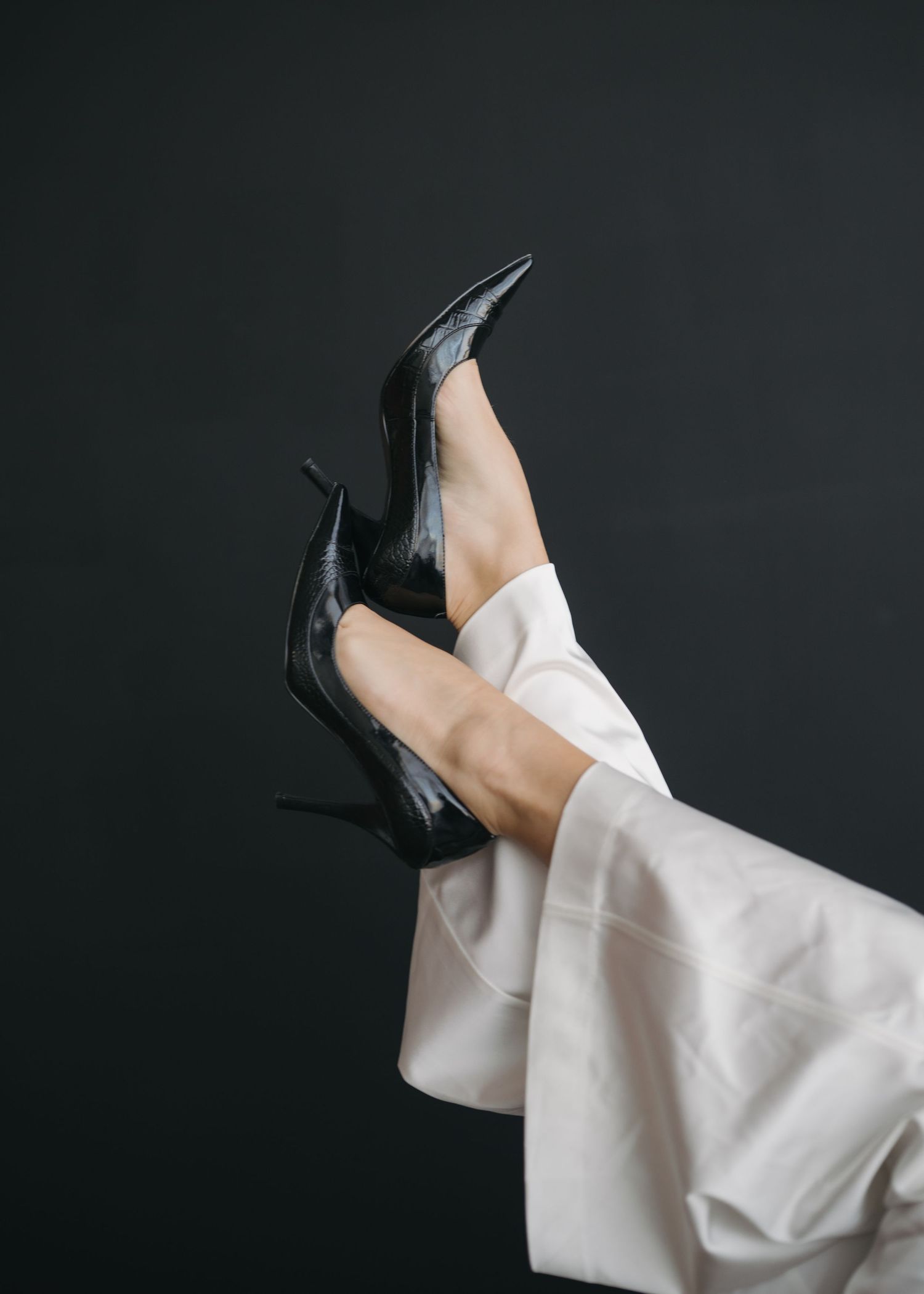 A white sleeve of a dress shirt or garment shown in motion against a dark background, creating an artistic flowing effect.