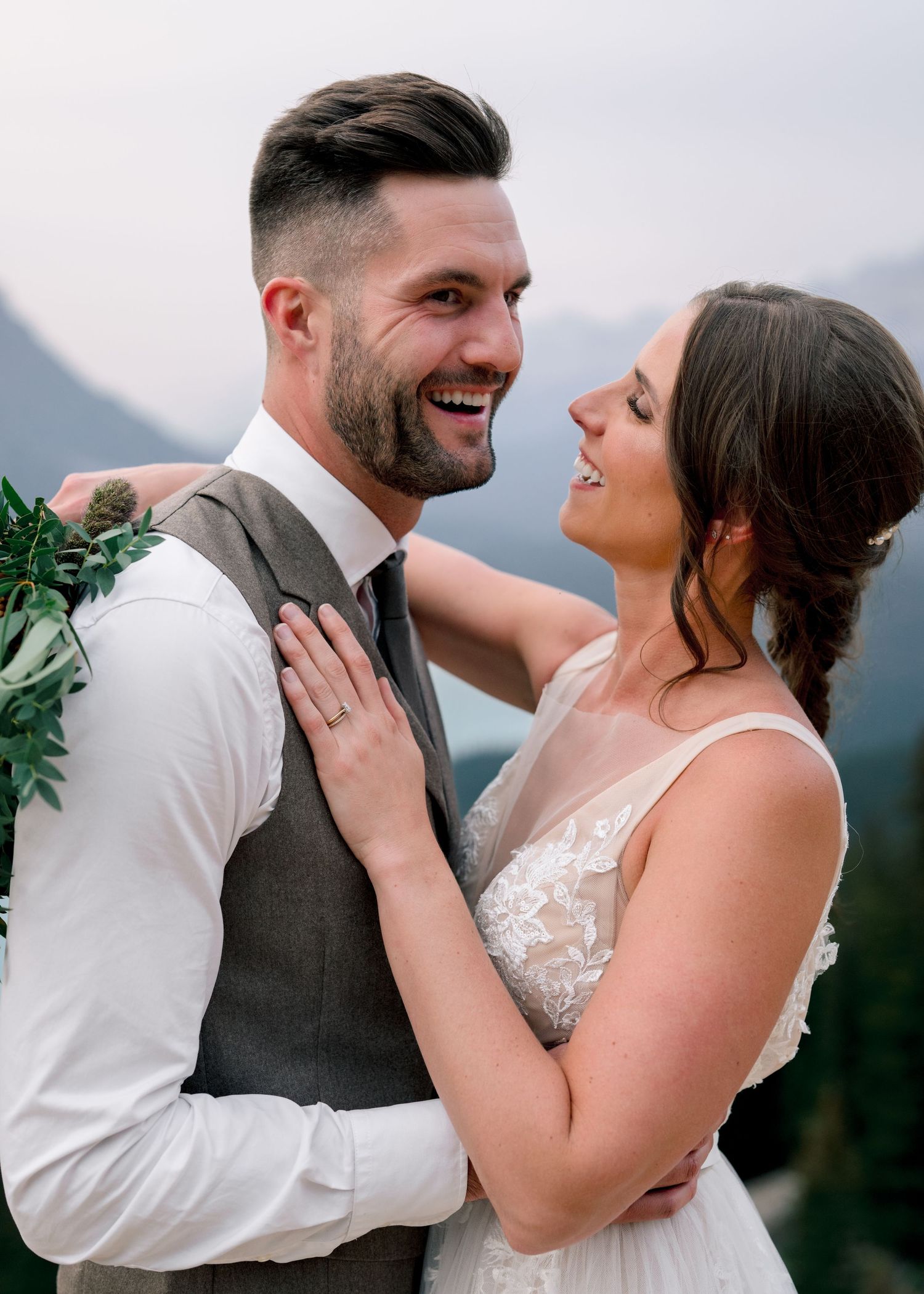 Happy couple embraces and laughs joyfully during outdoor mountain wedding photoshoot.