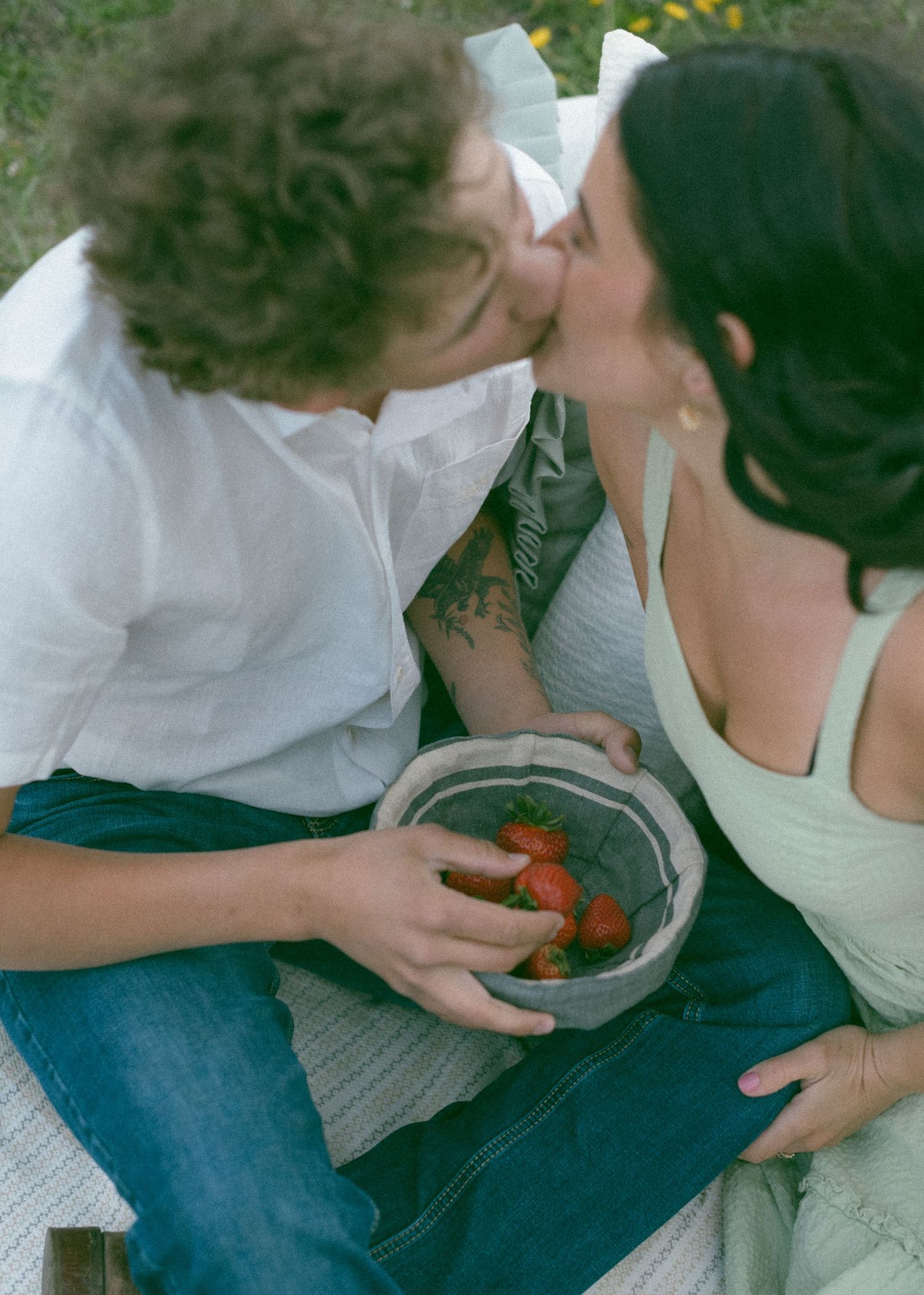 A romantic moment shared over strawberries during an outdoor picnic. Calgary Alberta Engagement Photographer.