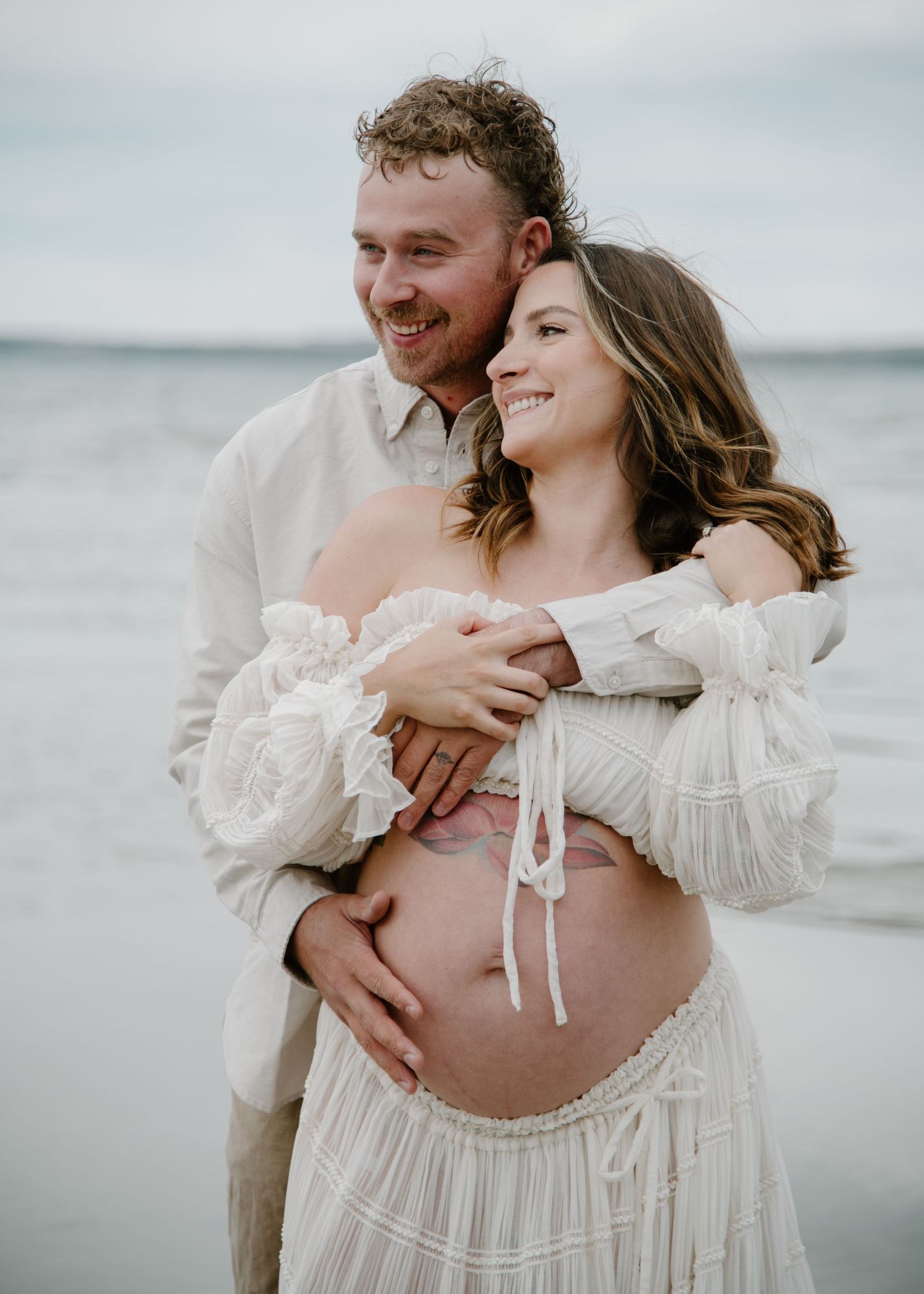 Maternity photoshoot on beach with couple in flowing white clothing. Calgary Alberta Maternity Photographer