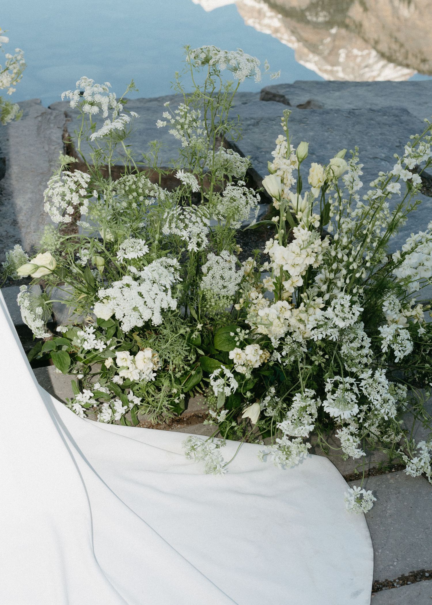 Close-up view of delicate white baby's breath flowers cascading over a weathered surface with ocean background.