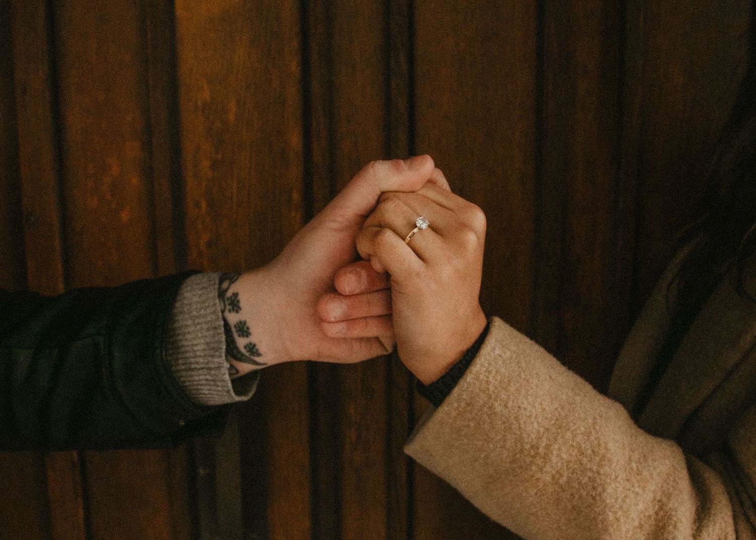 Hands performing sequential gestures against a dark wooden wall background. Calgary Alberta Engagement Photographer.