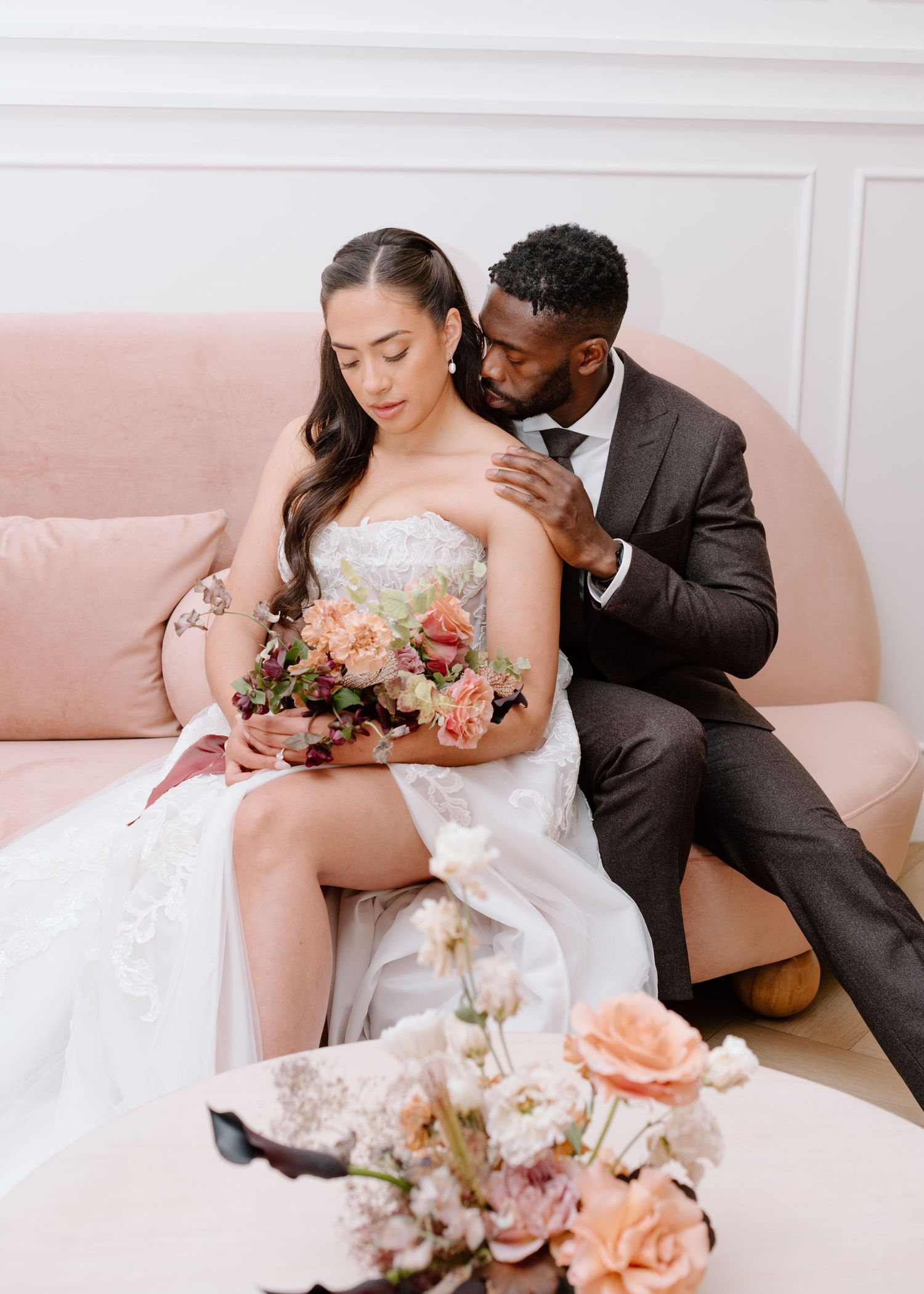 Romantic couple portrait on pink sofa with peach and white floral bouquet at the Studio at Vic Park YYC Calgary Wedding Photographer