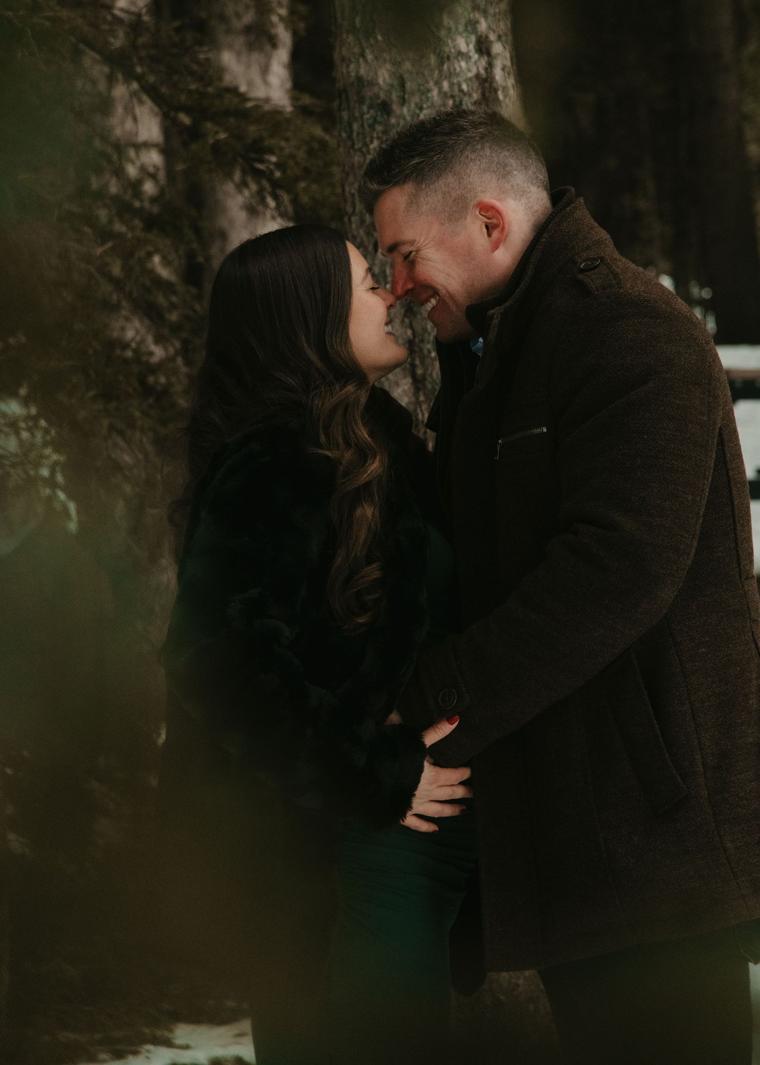 Romantic couple sharing an intimate moment against a dark moody background. Calgary Maternity Photographer