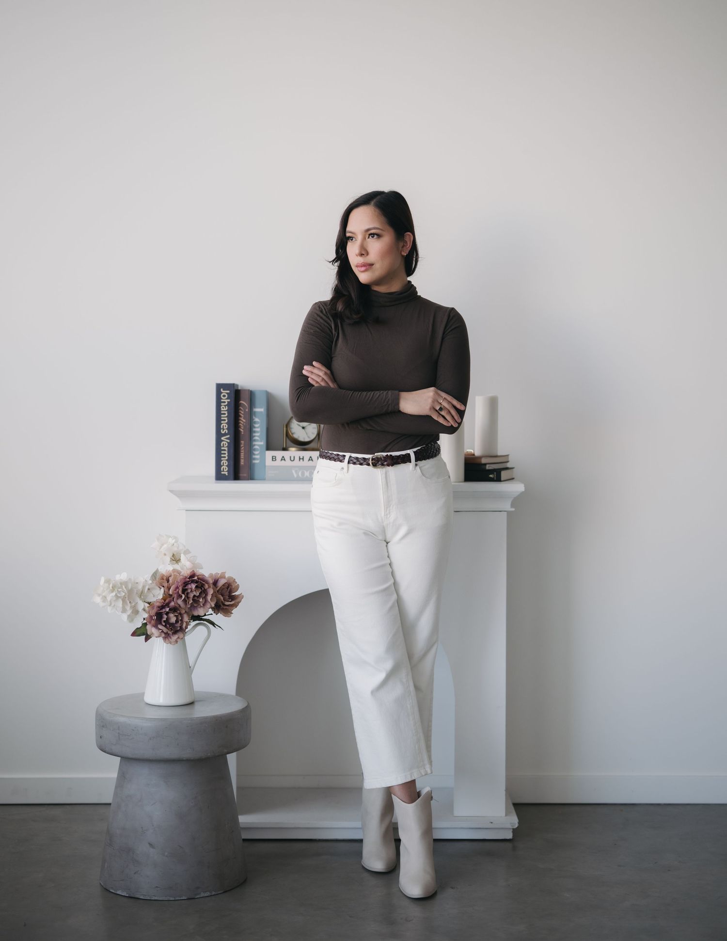 A minimalist fashion series showing a dark turtleneck with white pants styled against a light gray background.