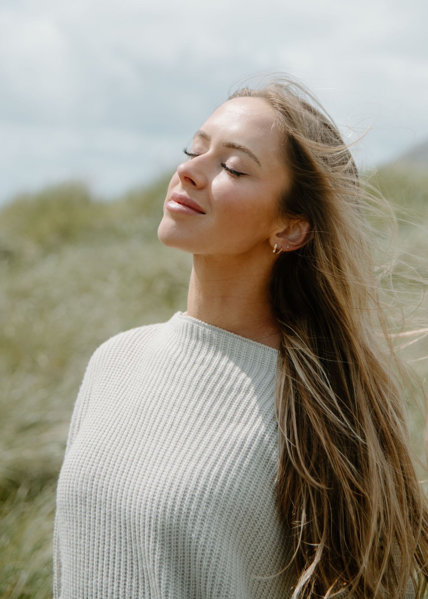 Peaceful portrait with closed eyes and flowing hair showcasing serenity in natural coastal setting on Oregon Coast. Calgary Lifestyle.