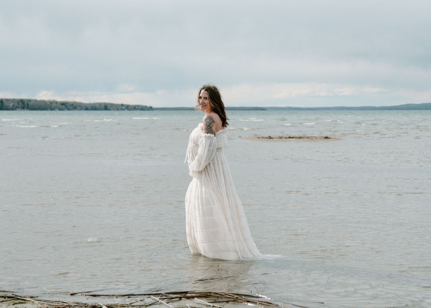 Ethereal white dress flowing in the breeze against a misty oceanfront backdrop. Calgary Alberta Maternity Photographer.