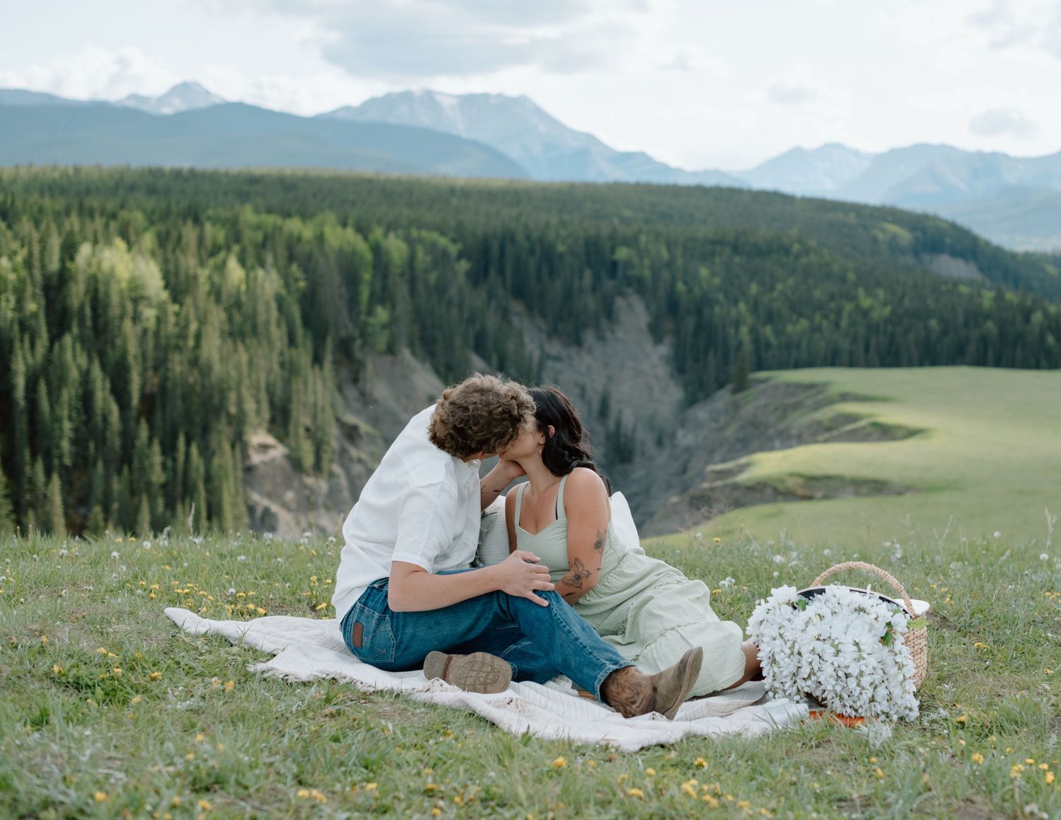 A picnic date on a blanket overlooking a scenic mountain valley. Calgary Alberta Engagement Photographer.