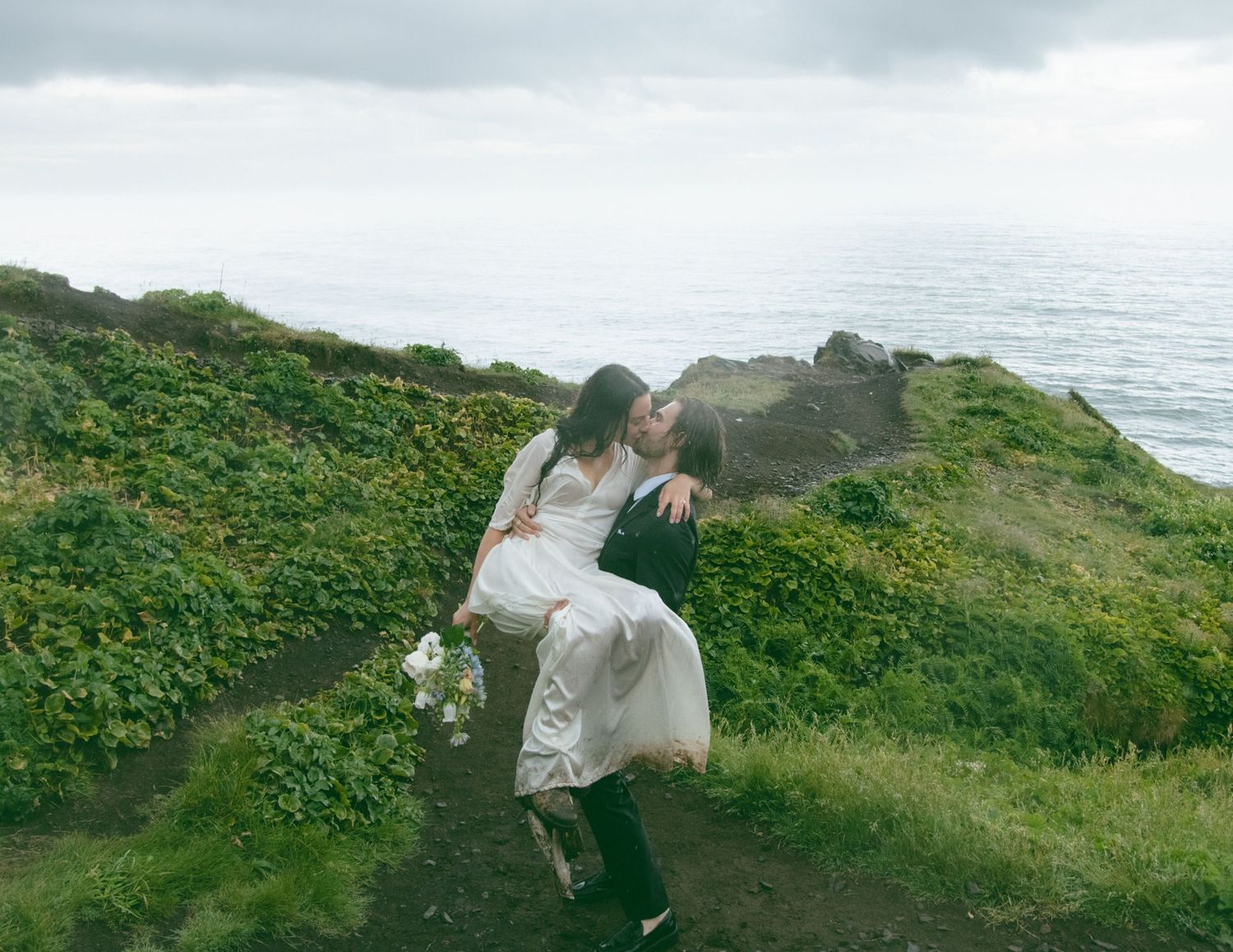 A joyful moment captured on a coastal hillside with the ocean in the background. Calgary Wedding Photographer