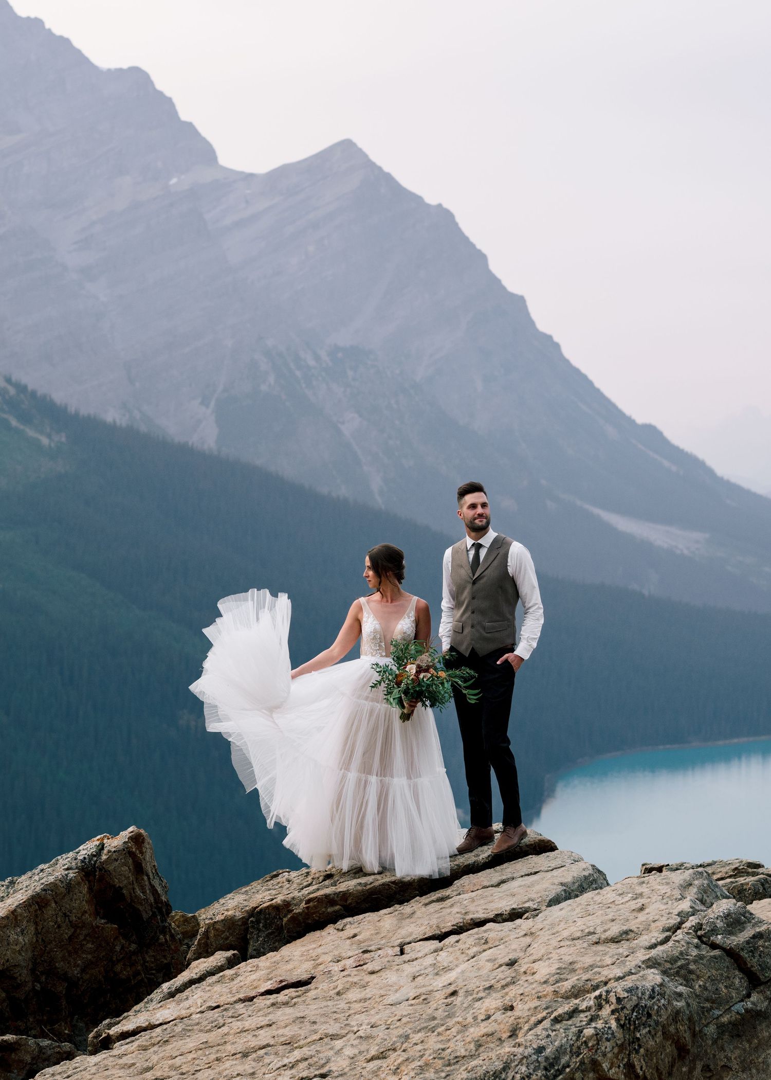 Romantic mountain elopement at Peyto Lake in Banff National Park with couple standing on dramatic rocky overlook.