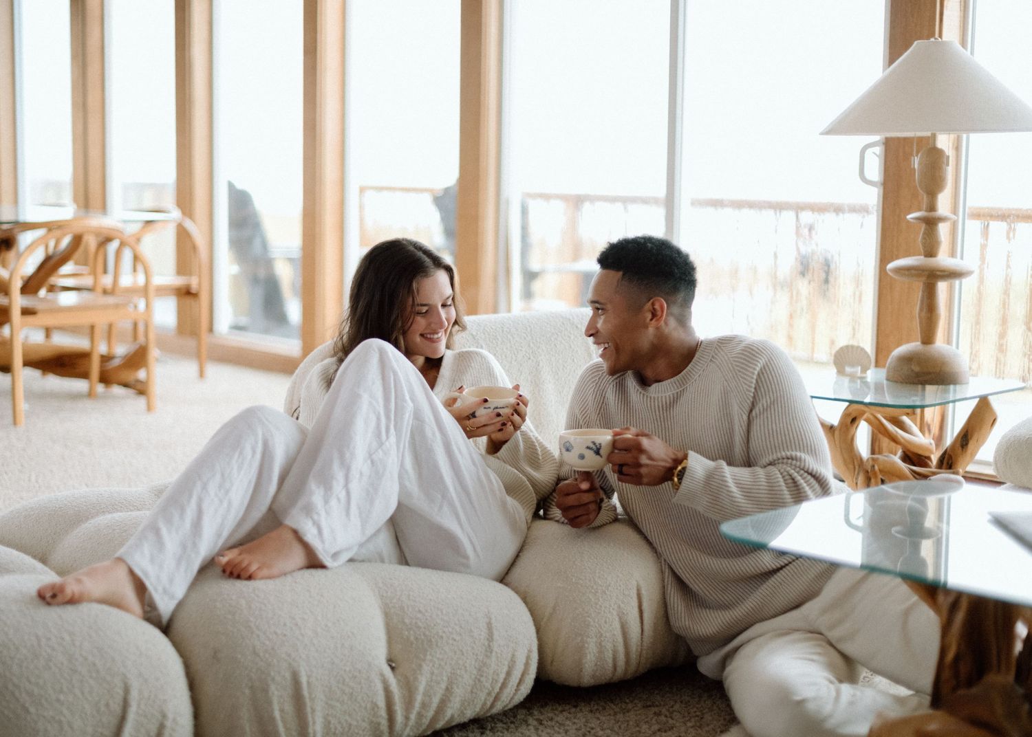 Panoramic sequence of couple relaxing and talking while lounging on white couch in sunny living room interior.